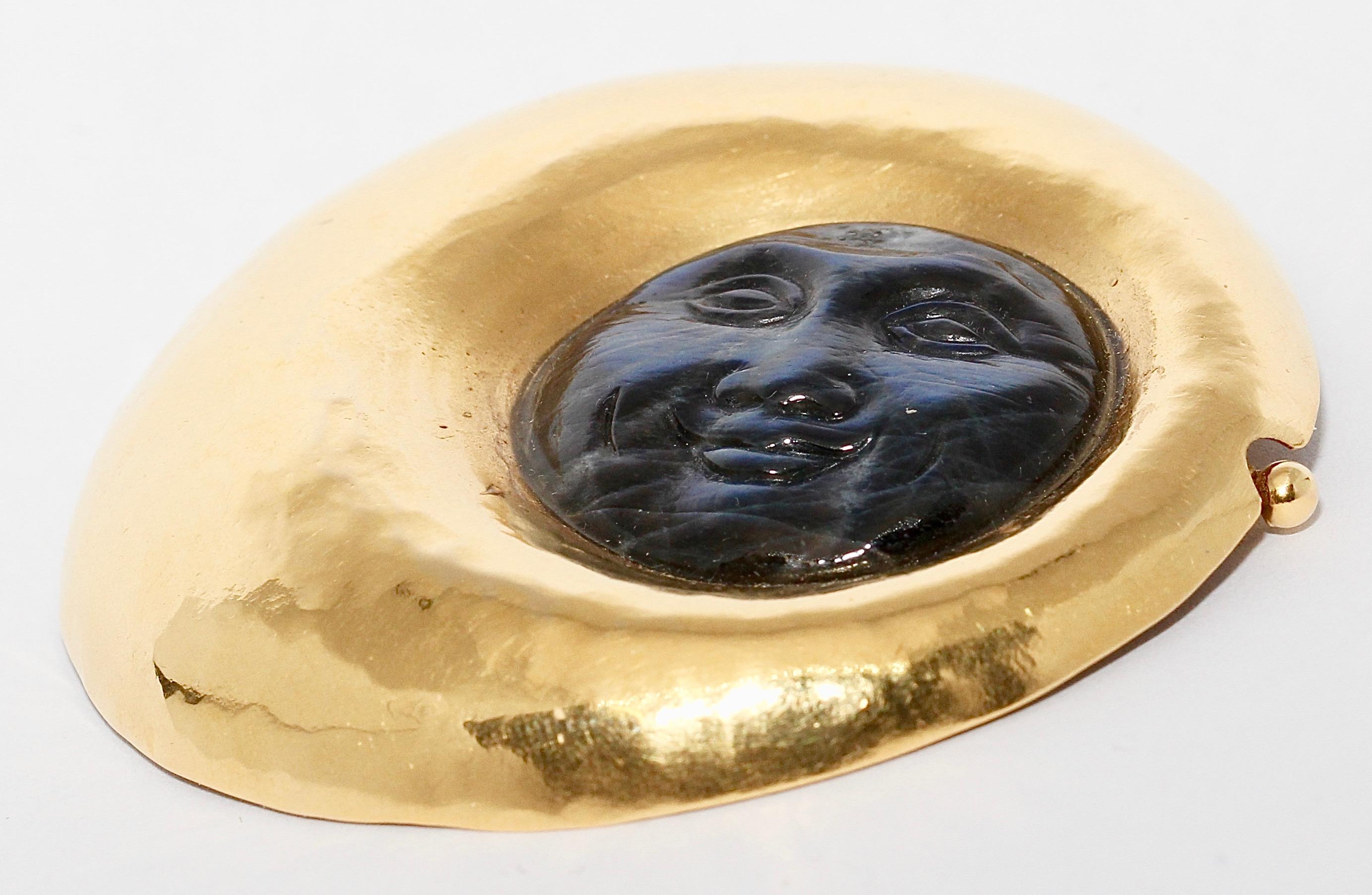 High quality designer gold brooch. 18 Karat gold, hammered. Laughing moon face of mother of pearl.

Hallmarked: 750, designer logo 