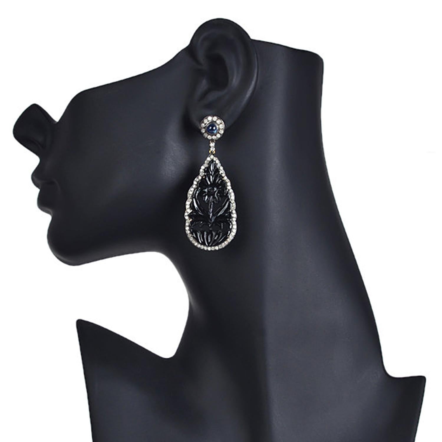 Designer Carved Onyx Drop Earring in silver and gold with blue sapphire is an evergreen piece.

18kt gold: 1.68gms
Diamond: 2.69cts
Onyx Black: 27.22cts
Sapphire:1 .3cts
