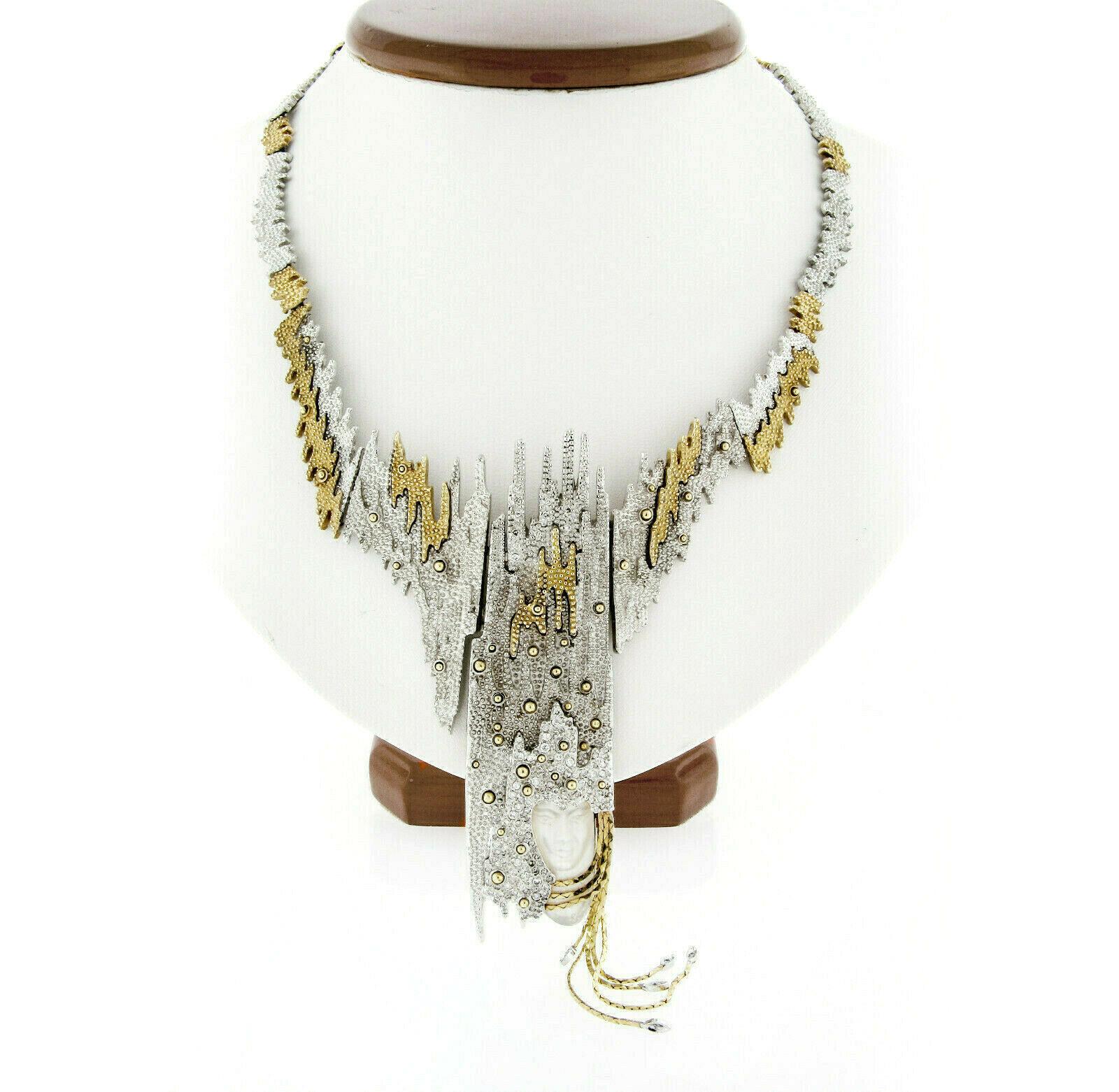 This limited edition necklace and brooch statement piece is designed by Russian-born French artist Erte, Romain de Tirtoff. It is crafted in solid sterling silver and solid 14k yellow gold, and features uniquely textured links decorated with fine