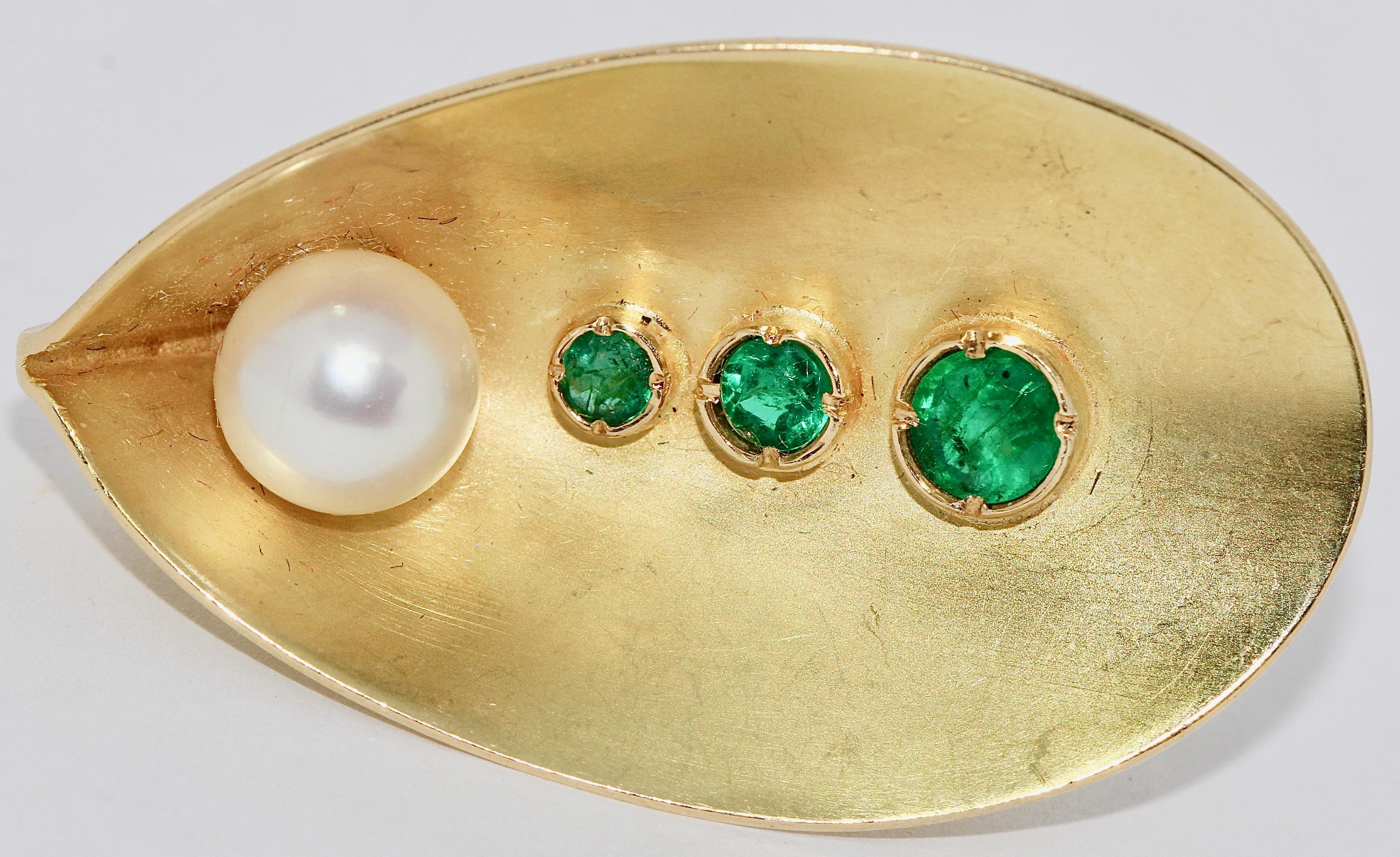 Eye-catching, solid designer ring in 18 Karat gold with emeralds and a pearl.

Hallmarked: 750.

US Ring size 7