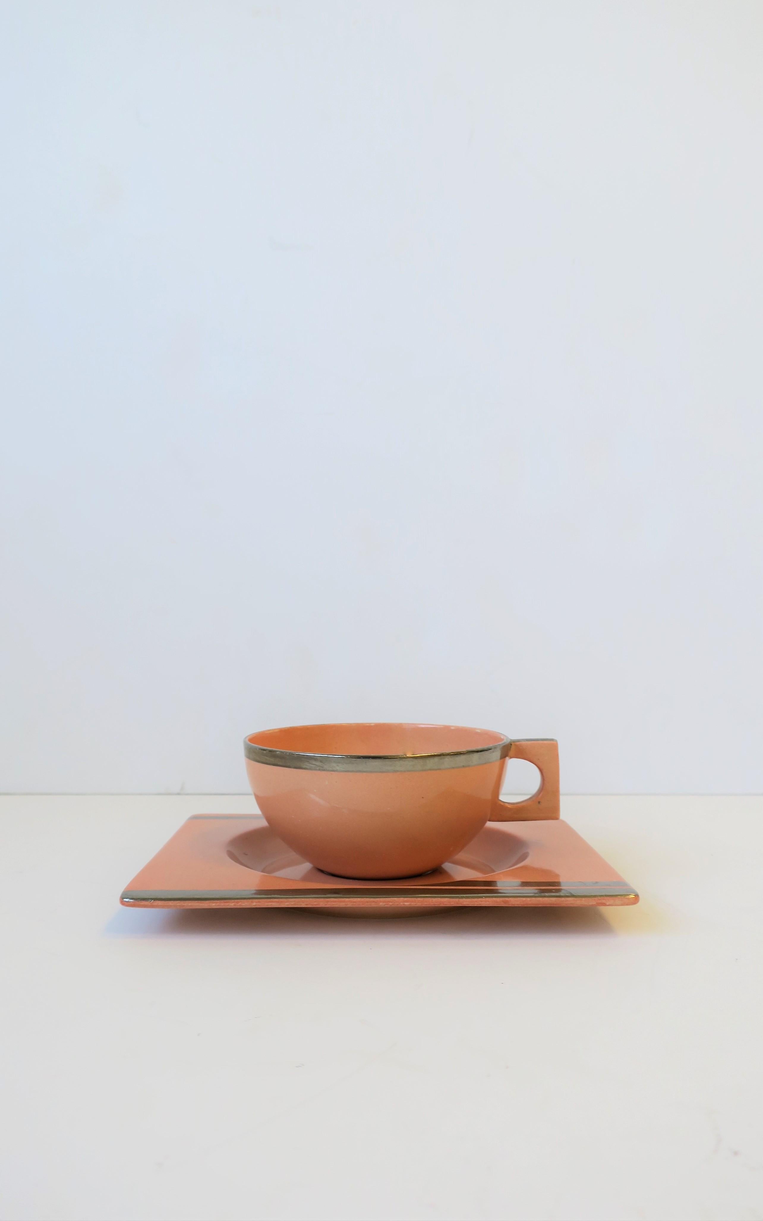 A gorgeous French Art Deco period coffee or tea cup and saucer set by designer Jean Luce, circa 1930s, France. Cup and saucer are a salmon pink hue with silver detailing. Maker's mark 