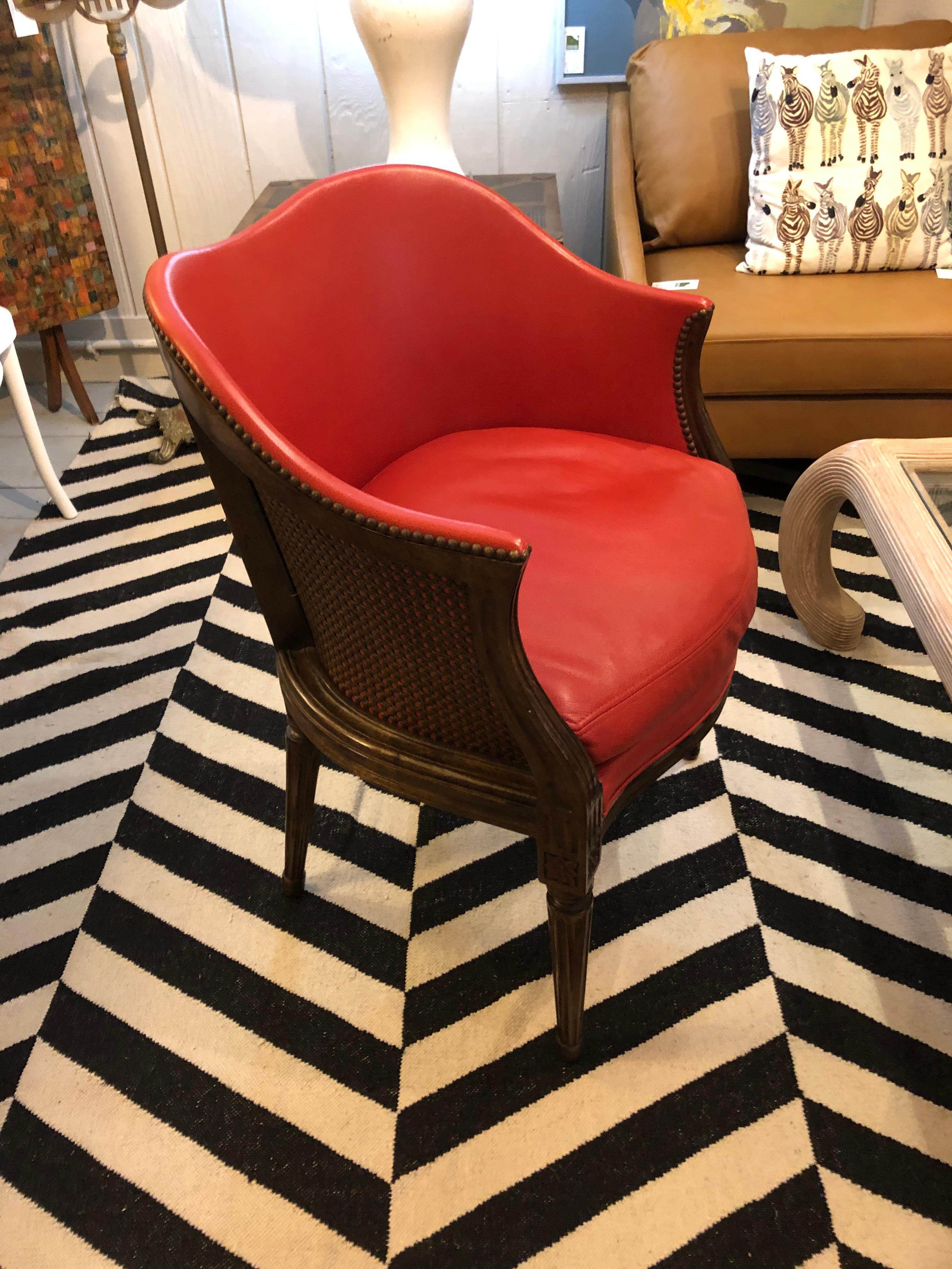 Handsome designer carved walnut curved tub chair having tobacco caned back and stunning burnt orange leather upholstery finished with nailheads. The scalloped back is a sensual touch.