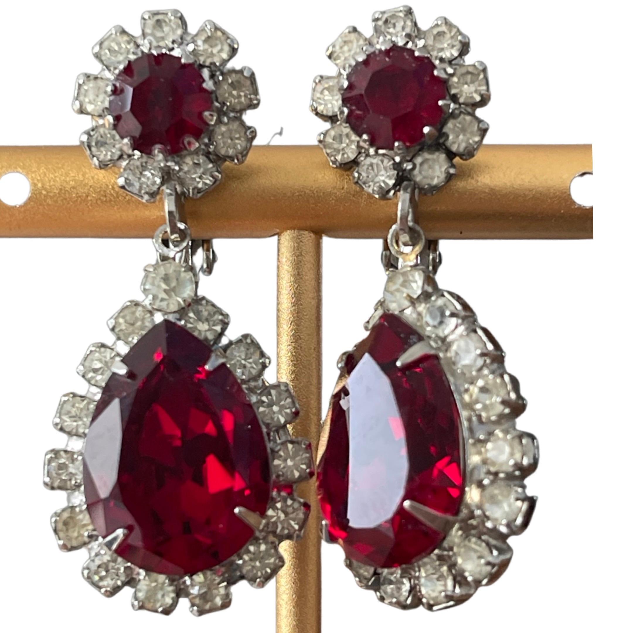 Elegant drop-style earrings that feature one of designer Louis Kramer, extraordinary designs. A red flower Austrian crystal ruby drops into another pear-shaped red Austrian crystal both surrounded by the highest quality Austrian rhinestones. 

In
