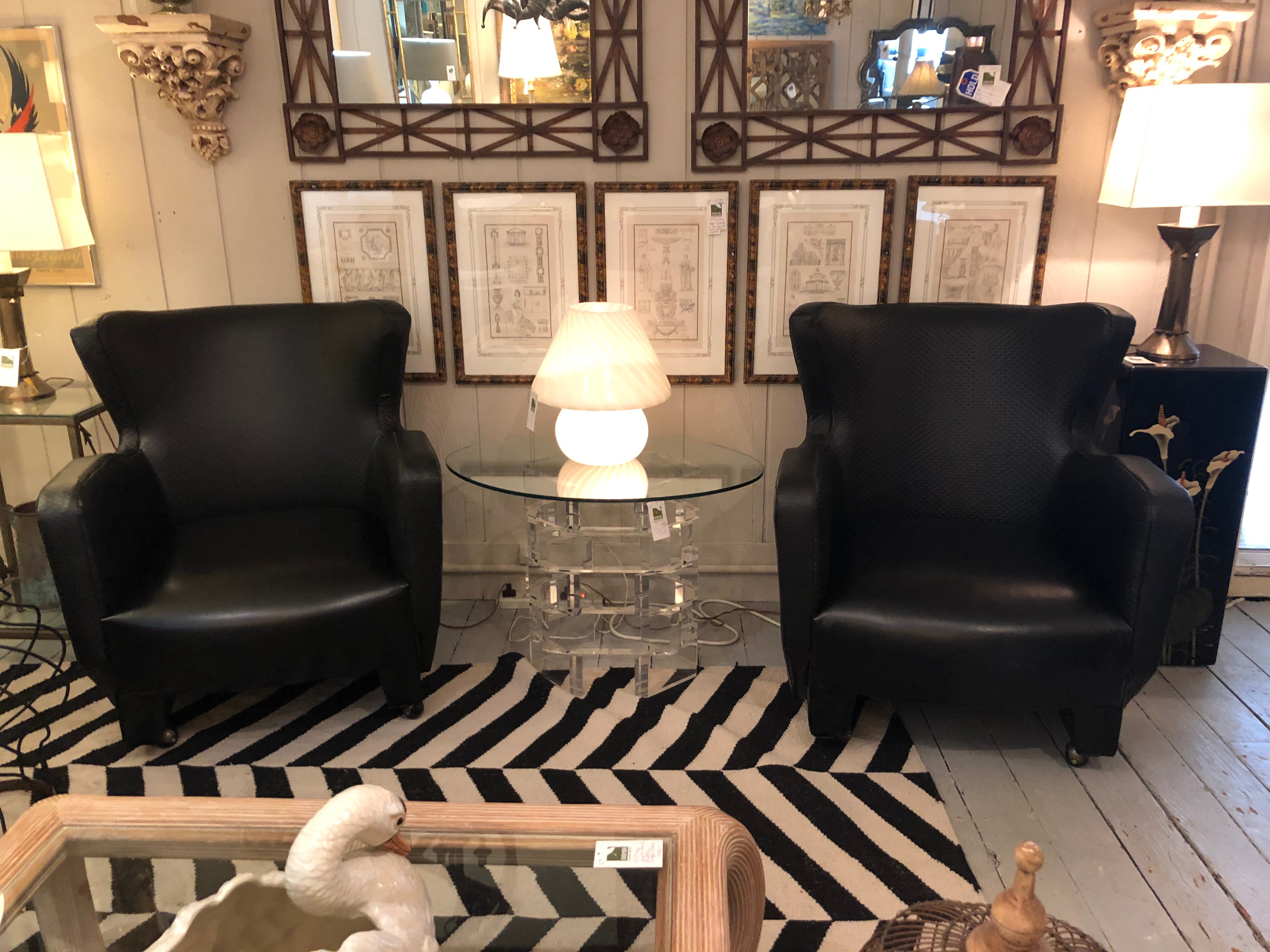 Striking sophisticated pair of iconic Milo Baughman for Thayer Coggin black leatherette club chairs having subtle quilting to the leather everywhere but the seat. Black casters on the bottom. Label underneath.