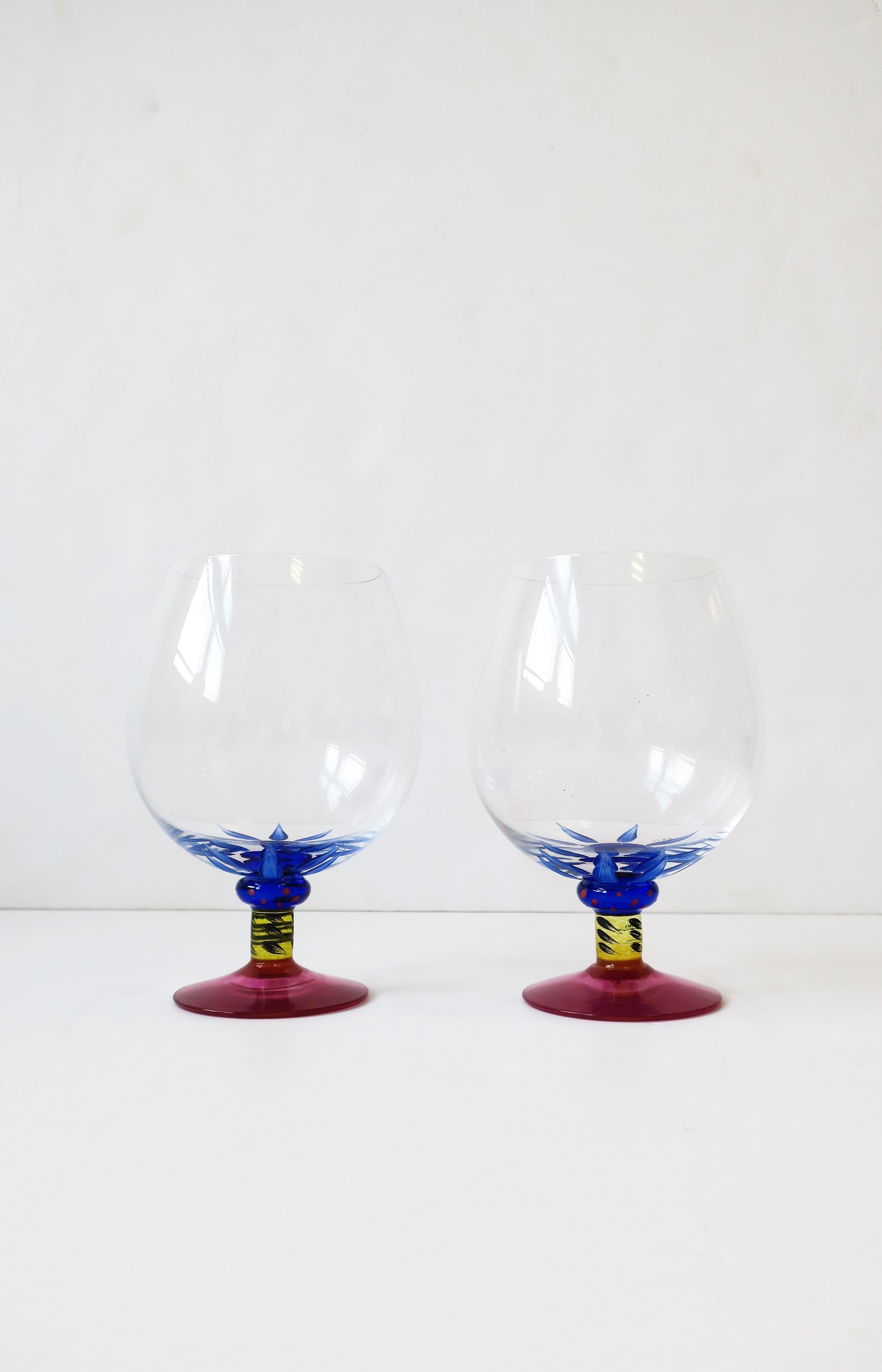 A beautiful pair of Postmodern art glass cocktail or brandy cognac liquor spirits glasses by Designer Ken Done for Kosta Boda, Sweden, circa 1990s. These beautiful crystal and art glass glasses are hand painted and hand blown; Base/stem is a cobalt