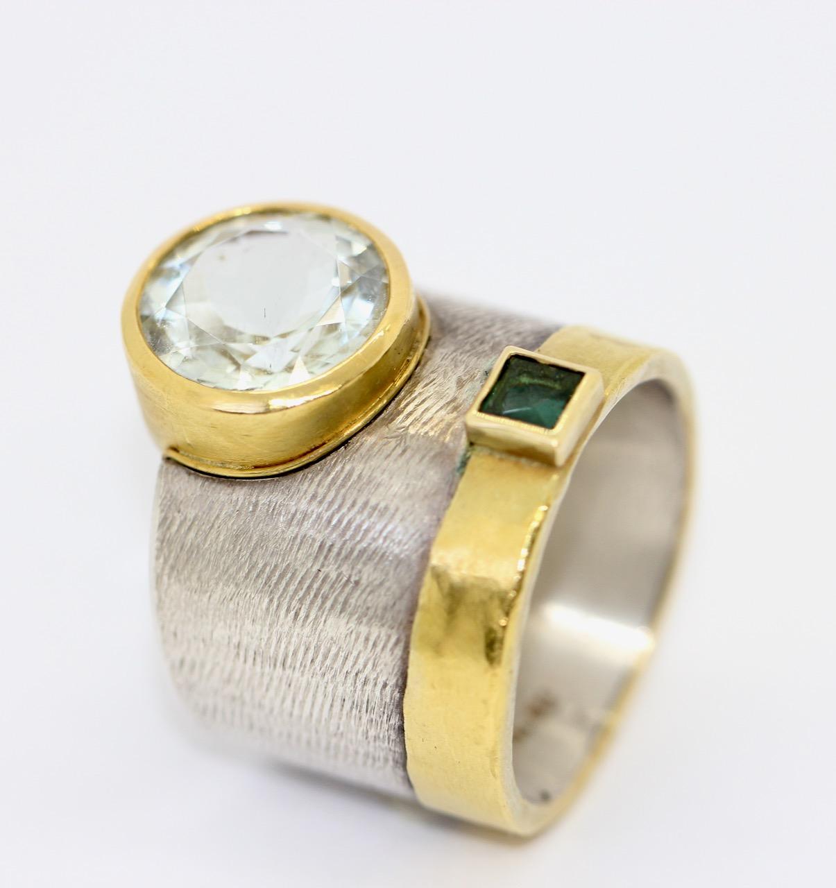 Fancy, solid and heavy designer ring made of sterling silver and 21.6 Karat gold with aquamarine and tourmaline.

Hallmarked. One of a kind by a master goldsmith.

Includes certificate of authenticity.