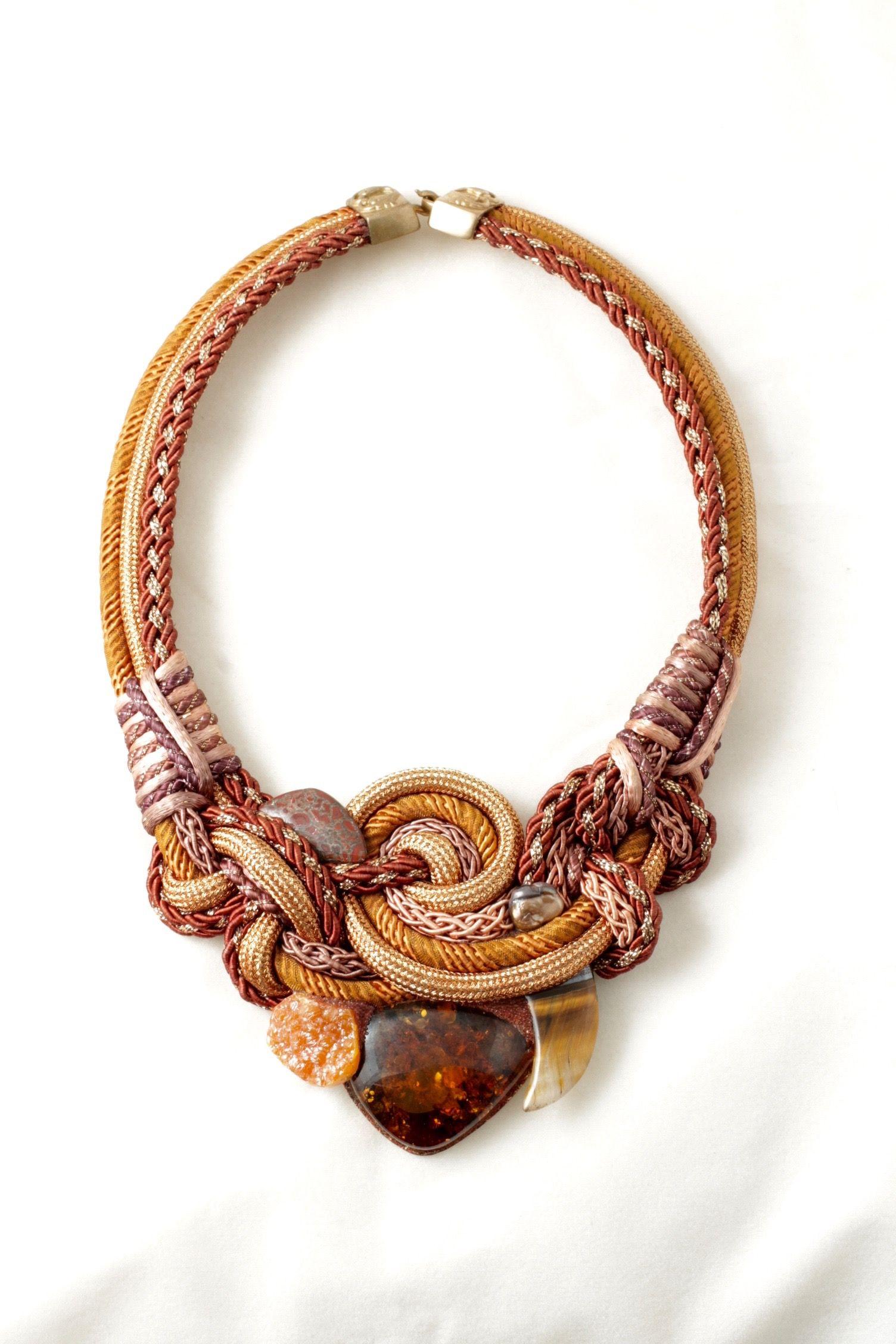 Semplicemente bello! La firma di Alex & Lee è una splendida collana a pettorina in ambra baltica multiforme, osso di dinosauro, citrino botrioide, occhio di tigre, perla, cordoncino annodato e avvolto a mano, chiusura in verme. La collana misura