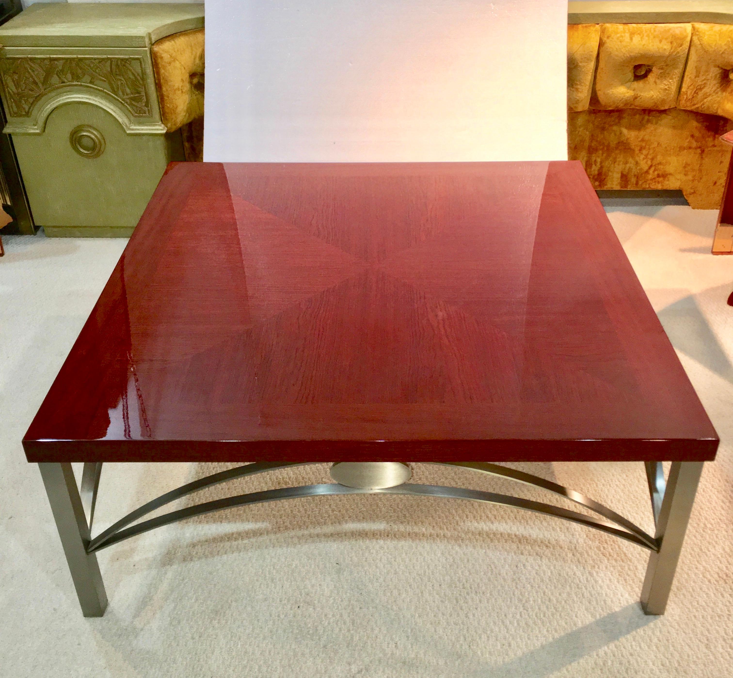Vintage 1980s cocktail table with high gloss polished bookmatched Padauk square top on a brushed stainless steel base comprised of square legs and double arched stretchers embellished with hefty oval medallions. Maker unknown but superb quality.