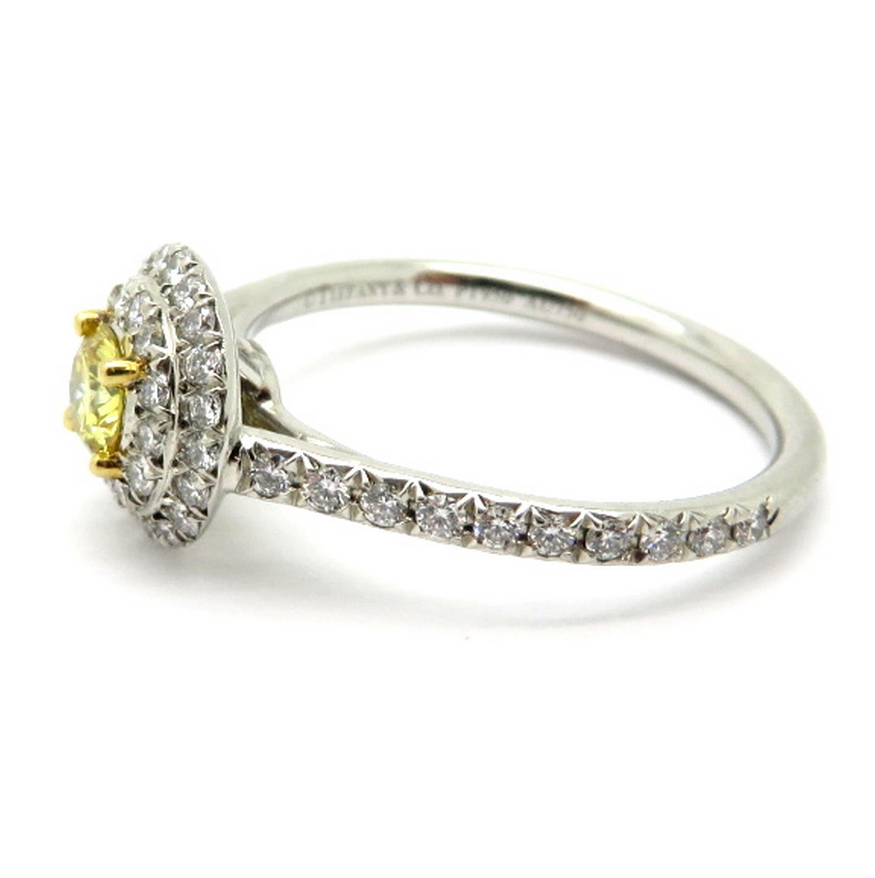 Designer Tiffany & Co. platinum and 18K yellow gold fancy vivid yellow double halo diamond engagement ring. Centering one round brilliant cut fancy vivid yellow diamond, four prong set, weighing approximately 0.23 carats, having VS1 clarity.