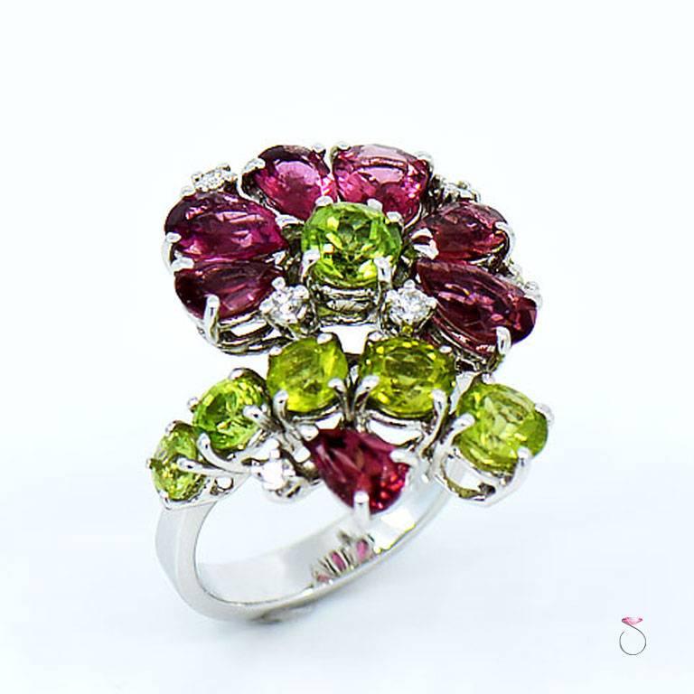 This stunning ring features a floral cluster of pink tourmaline, peridot & diamonds designed by Assor Gioielli. The ring is beautifully crafted in 18K white gold and all diamonds and gemstones are securely set in four prongs. The ring contains 0.14