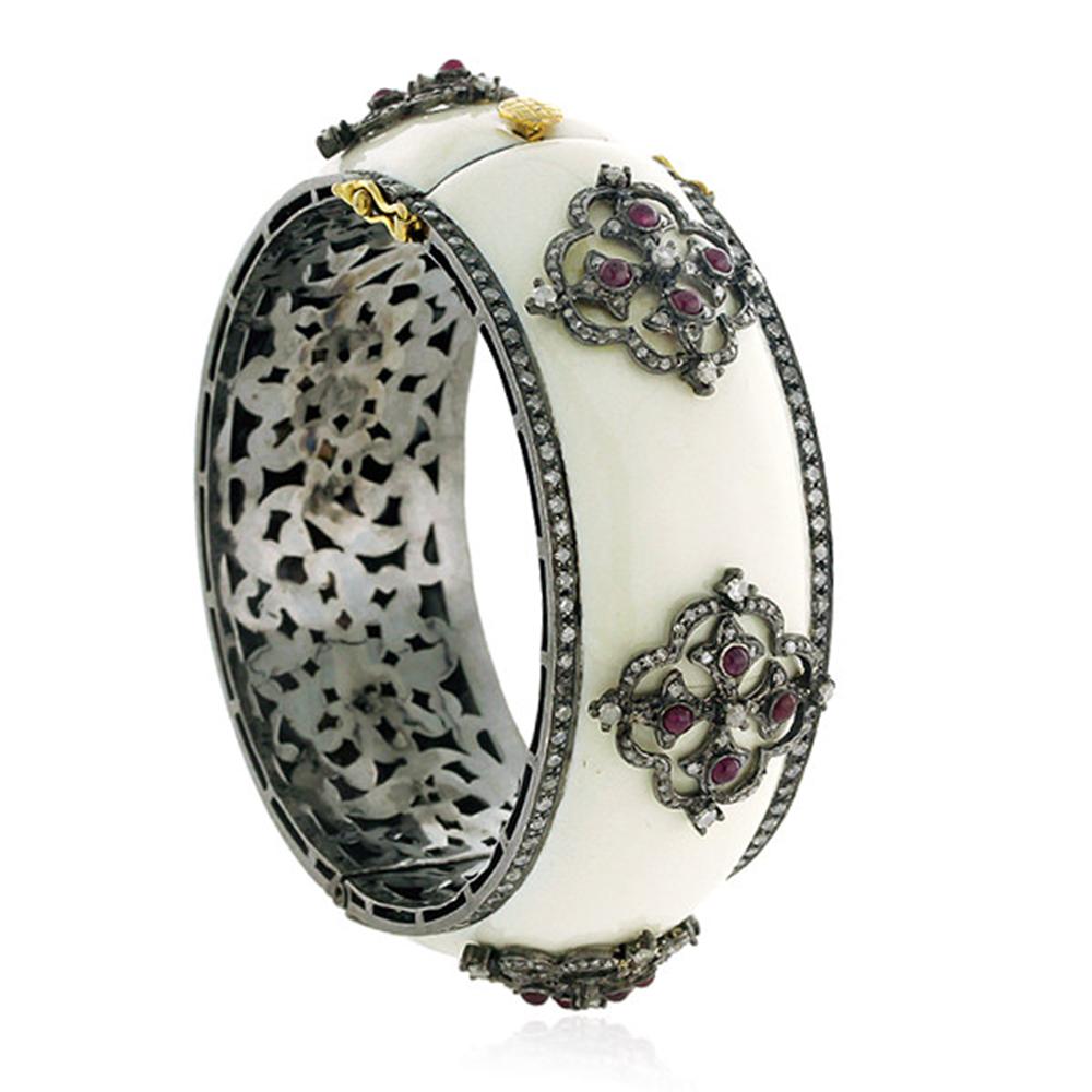 This designer White Enamel Cuff Bangle with Diamond and Ruby motif is set in Gold and Silver is lovely.

18kt Gold:2.63gms
Diamond:4.99cts
Silver:61.69gms
Ruby:2.9cts

