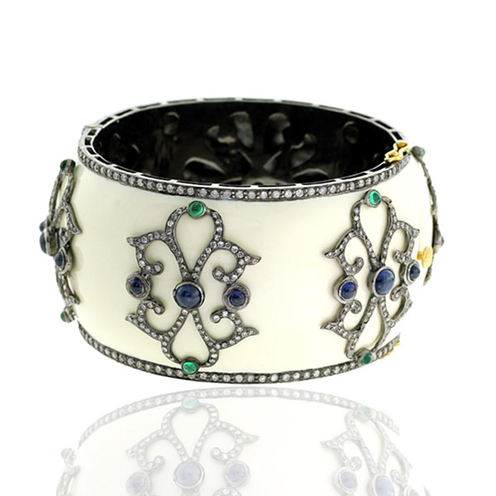 This designer White Enamel Cuff Bangle with Diamond and Sapphire motif is set in Gold and Silver.

18kt Gold:3.86gms
Diamond:4.99cts
Silver:86.26gms
Sapphire:6.90cts
Emerald:0.90cts