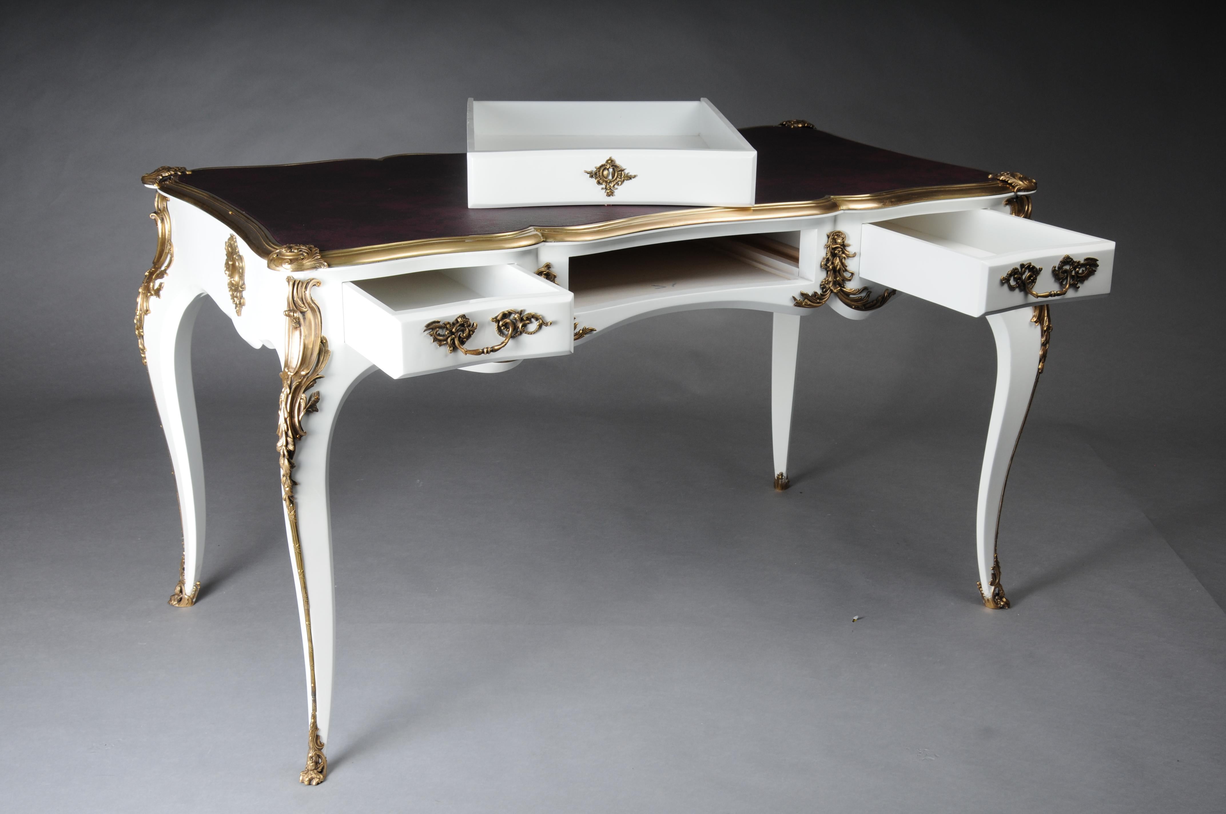 Bureau design/Bureau Plat en style Louis XV, blanc brillant et or

 Placage blanc poli sur hêtre massif avec applications de Rocaille. Très belles ferrures florales en bronze argenté en forme de goulottes, manipulées en bronze patiné.
Piétement très