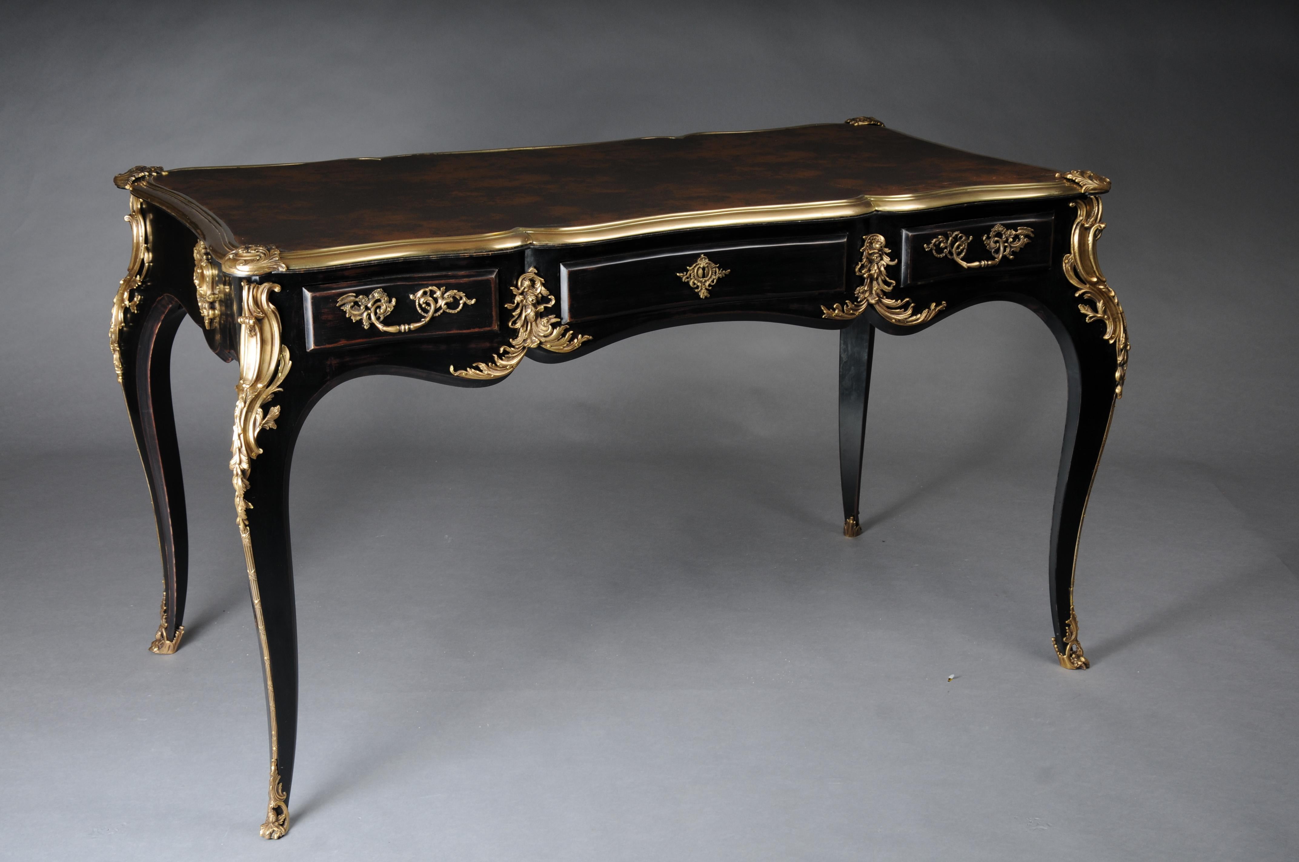 Scrivania / bureau plat di design nero in stile Luigi XV

Impiallacciatura nero pianoforte su legno massiccio di conifera con applicazioni rocaille. Finissimi accessori floreali in bronzo argentato a forma di scivoli, manici in bronzo patinato.
Base