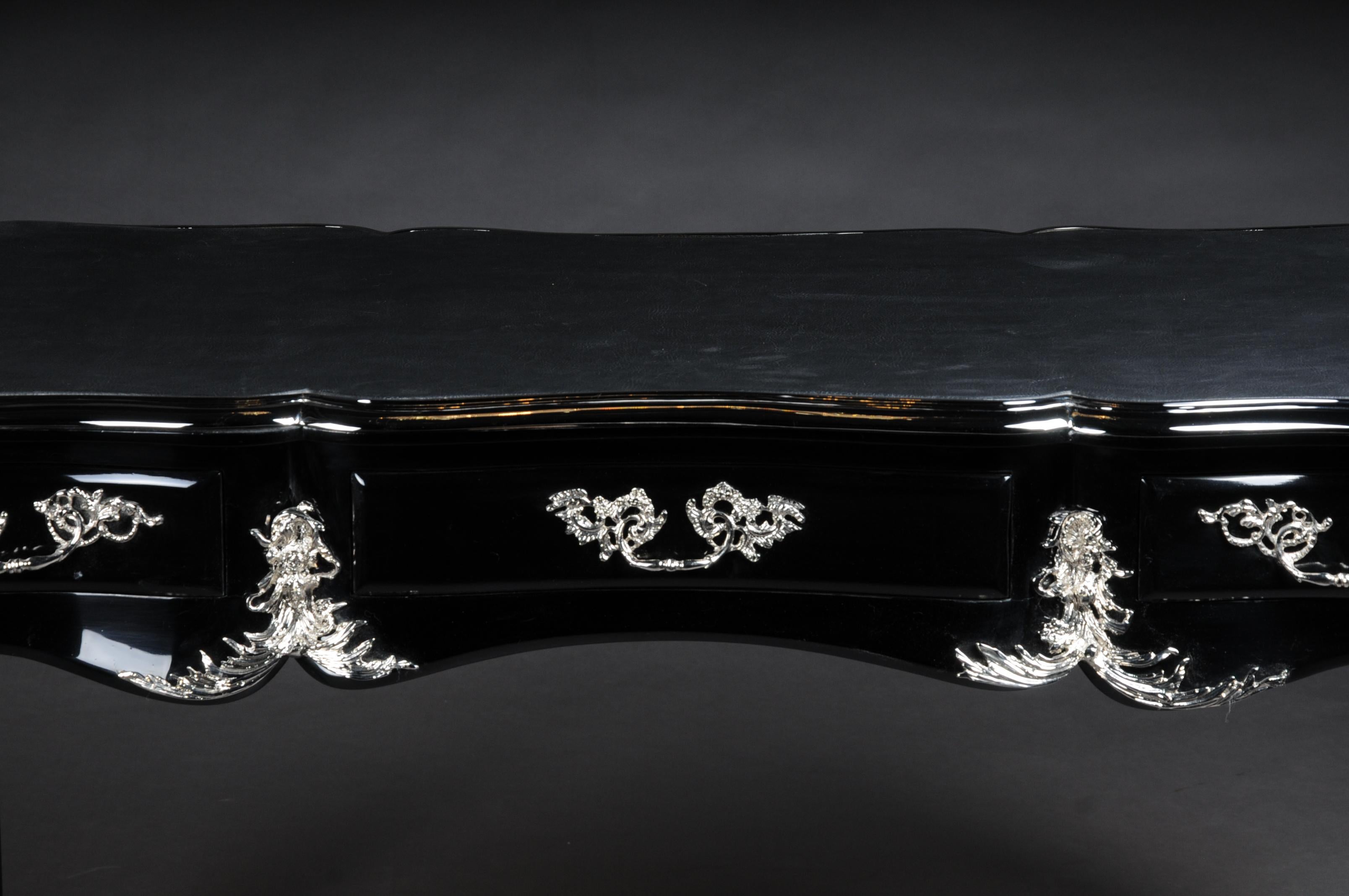 Black designer writing desk / bureau plat in Louis XV style

Piano black polished veneer on solid softwood with rocaille applications. extremely Fine, floral, silvered bronze fittings in the shape of chutes, handled in patinated bronze.
Very