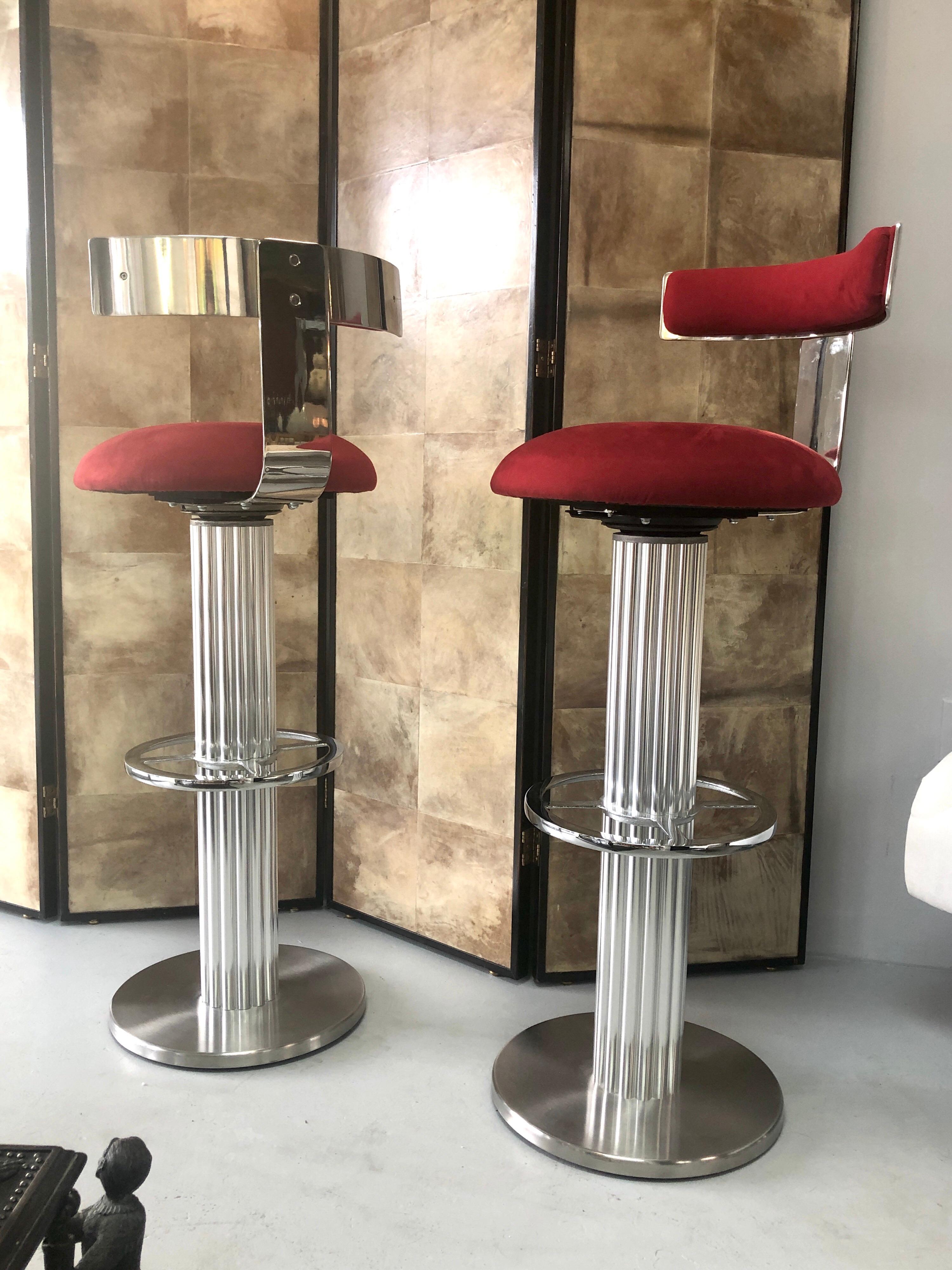 A great pair of bar stools by Designed for Leisure. Memory swivel seats. Retain the original red ultrasuede upholstery. The back and foot rest are mirror polished and the column has a satin finish. In very good condition, no issues.