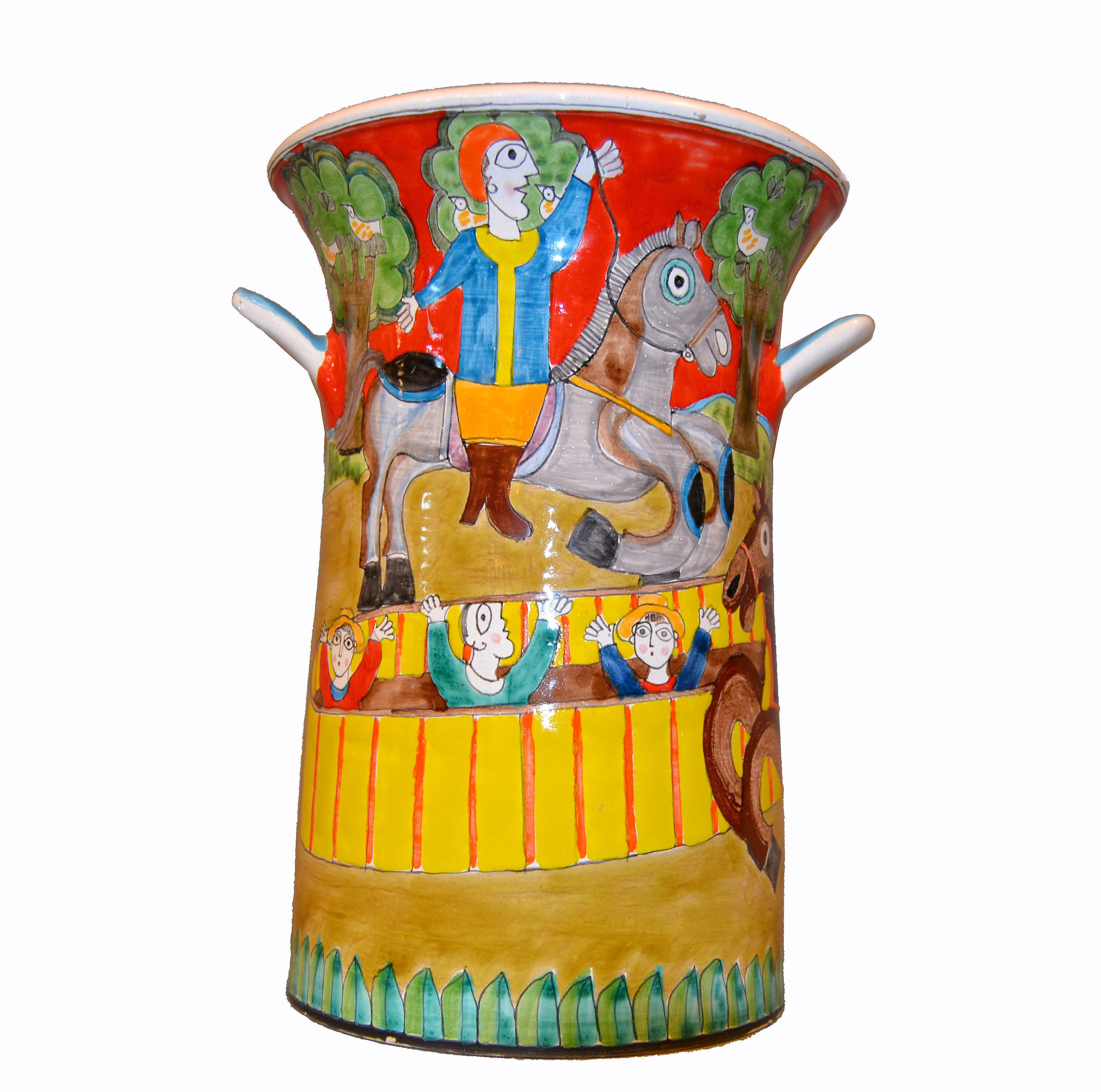 A glazed and colorful Giovanni Desimone hand painted pottery vase or vessel, circa 1969 from Italy.
The painting depicts two men on horses riding in a circus arena and people applauding them.
The vase is 14 inches high and 10 inches in diameter and