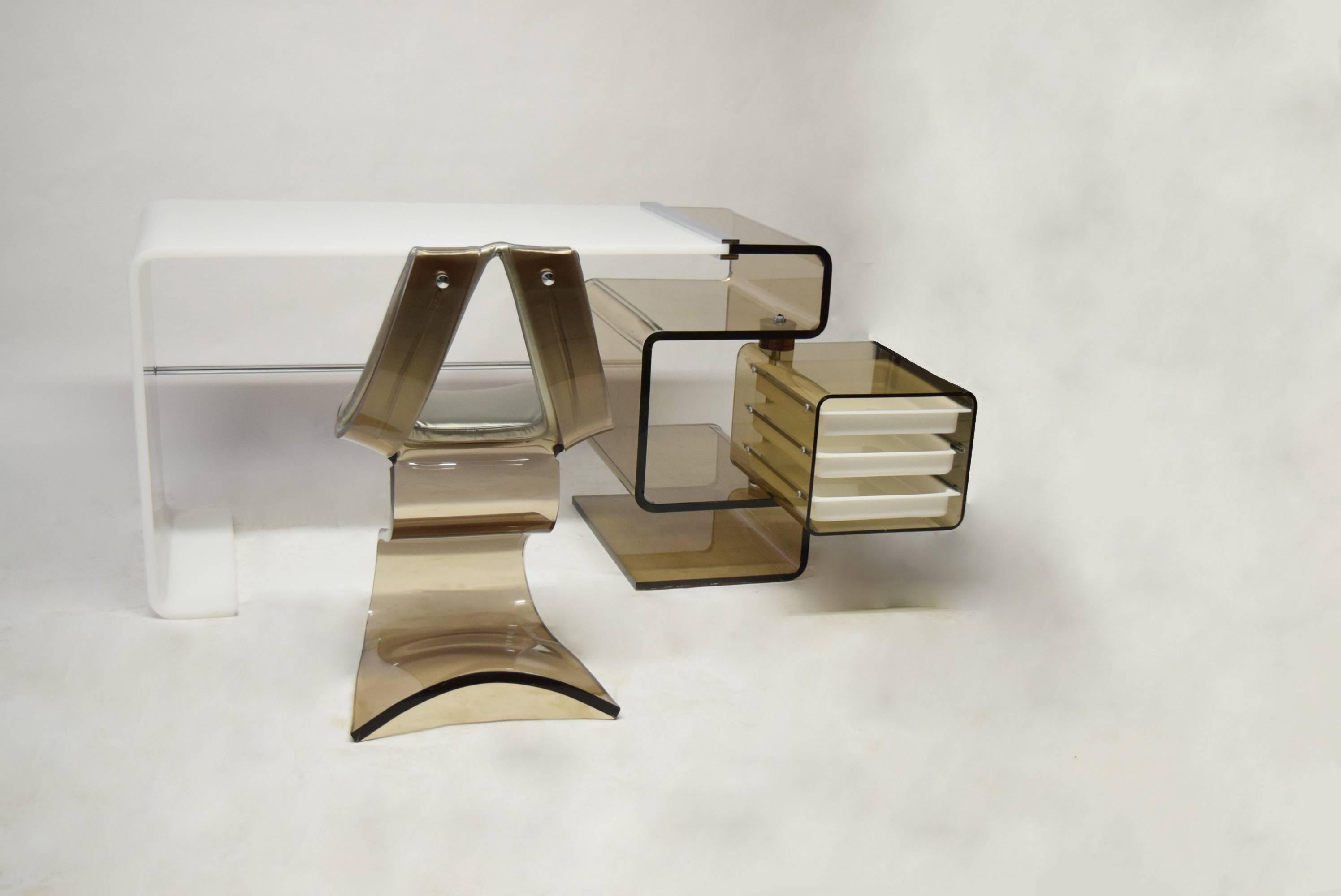 Desk with matching chair designed by Rena Dumas in 1971. The desk is white and smoked acrylic  with chrome hardware. The storage is smoked with three white drawers that swing out for access. 
The matching chair is also smoked with chrome hardware.