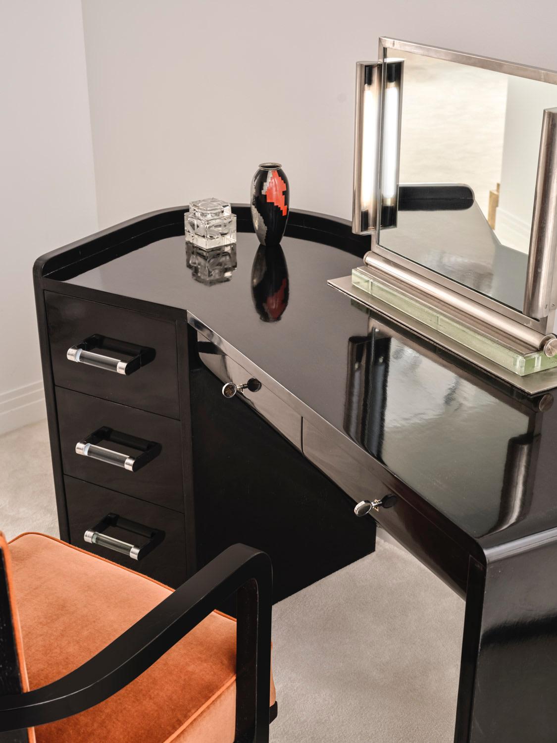 Der Schreibtisch ist mit schwarz lackiertem Ebenholz furniert.
Die Beine bestehen aus einem Kasten mit drei Schubladen mit Griffen aus Glas und verchromtem Metall auf einer Seite und einem massiven Sockel auf der anderen. 
Es öffnet sich mit zwei
