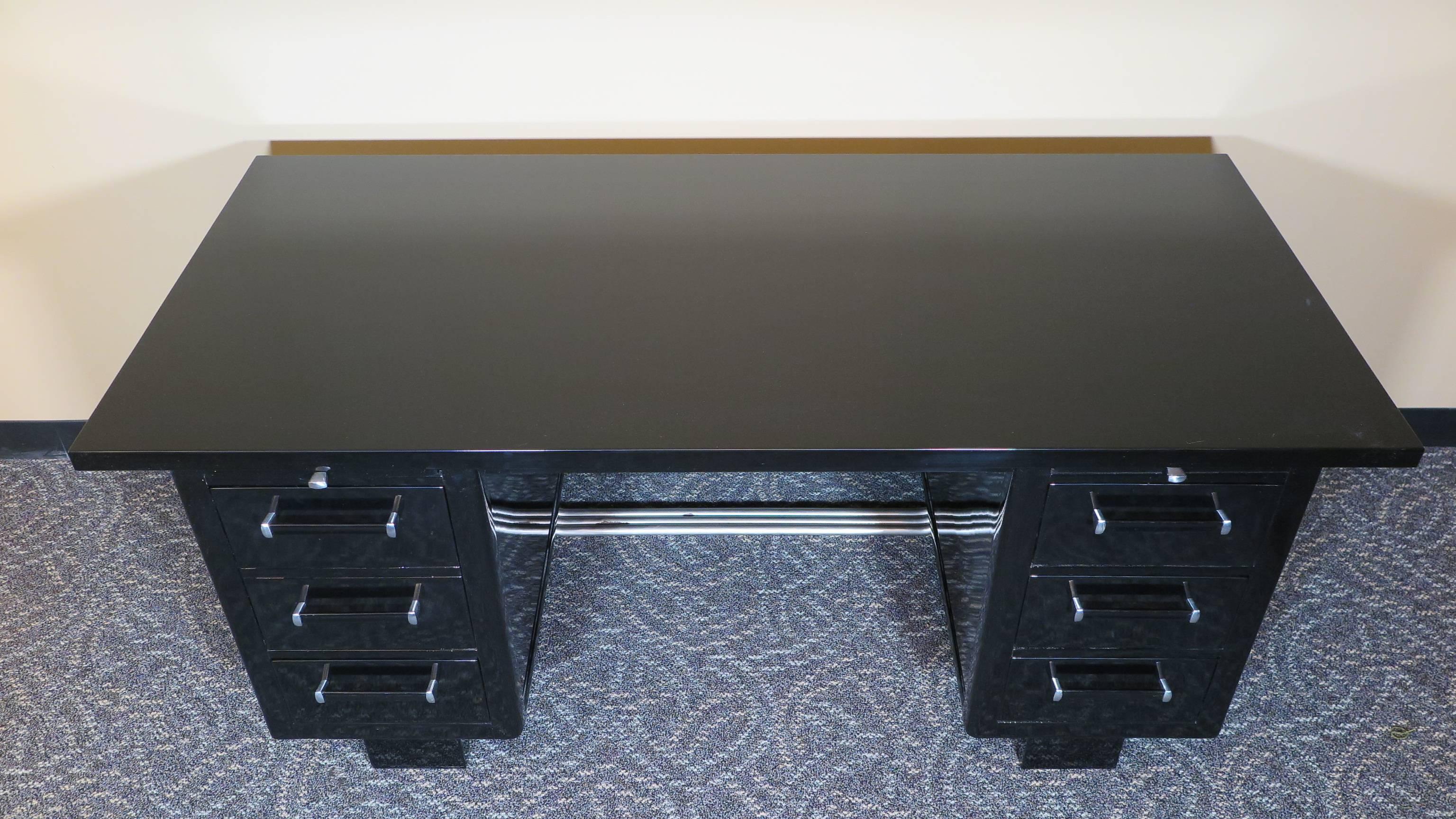 Black lacquer Art Deco desk. Art Deco black desk raised on plinth legs to the back and steel tubes brace detail as footing to the front of the desk. Writing platforms on both left and right side. Three drawers on the right and one drawer top with a