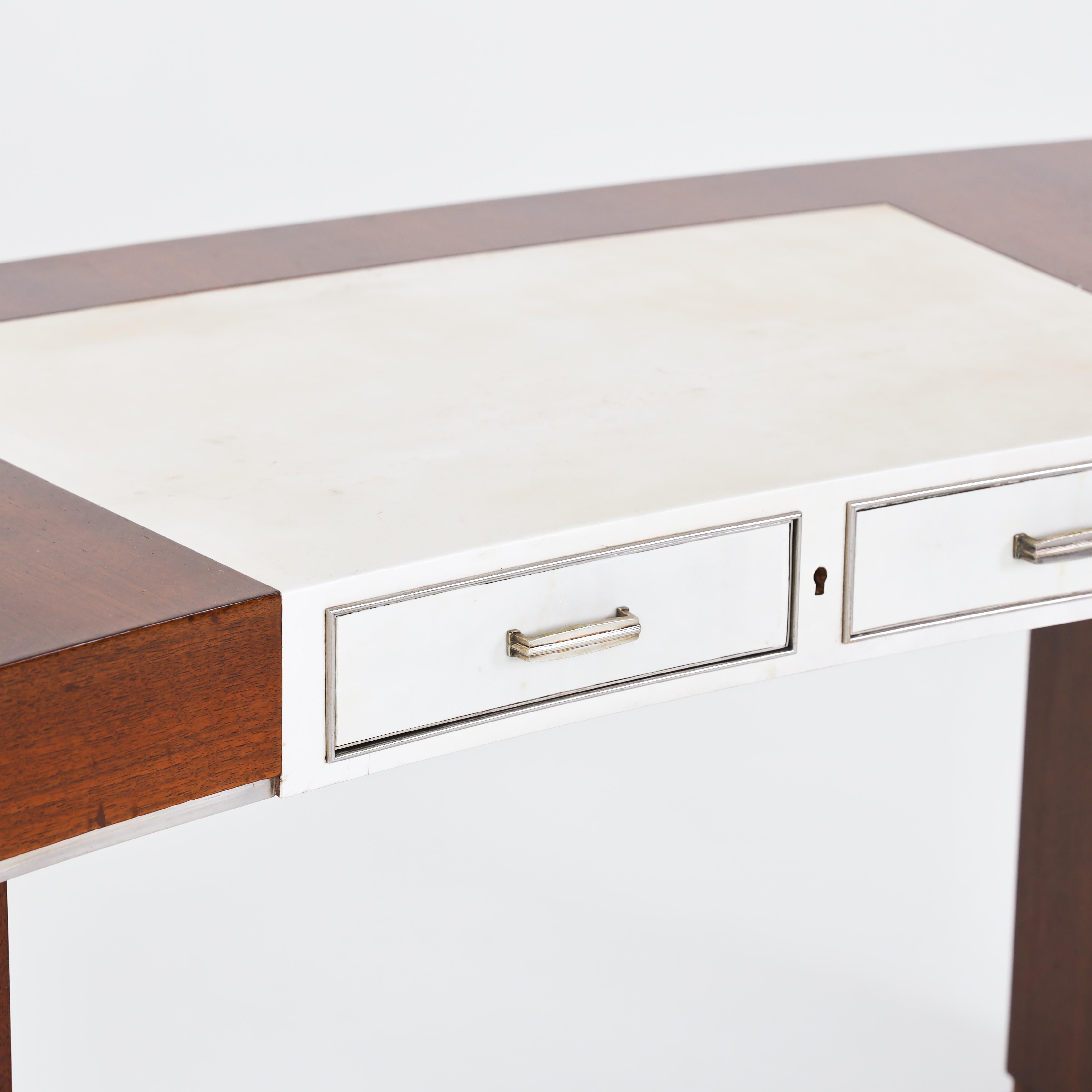 Art Deco desk on rectangular side panels with a flared base and slightly curved trapezoidal tabletop with two drawers. The central section is covered with a creamy white parchment (restored). The drawers, the legs, and the lower edge of the table
