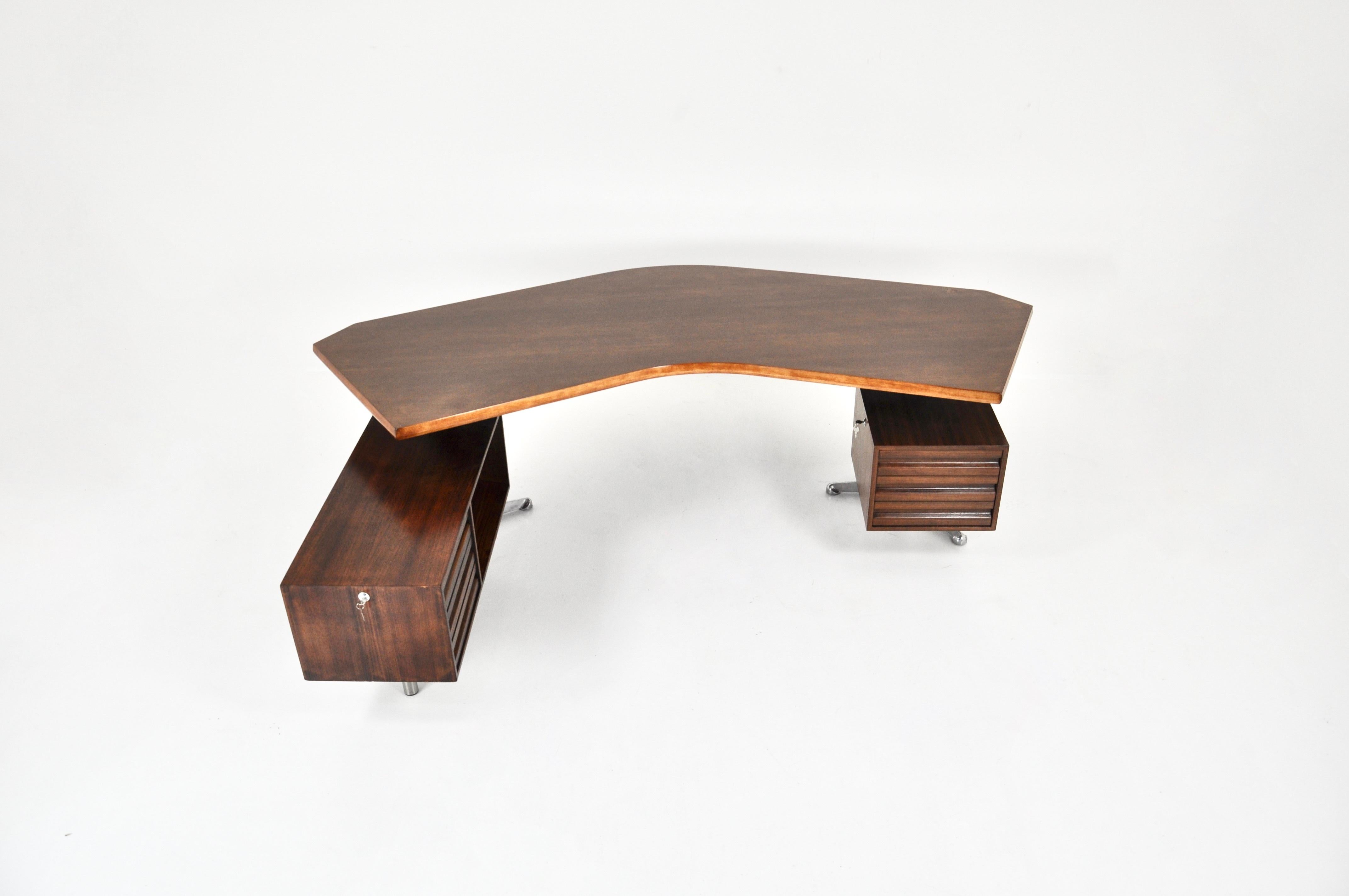 Wood and metal desk in the shape of a boomerang. Stamped Tecno. 2 modules, one with 1 large lockable drawer and another with 3 drawers and storage. Wear and tear due to the age of the desk.