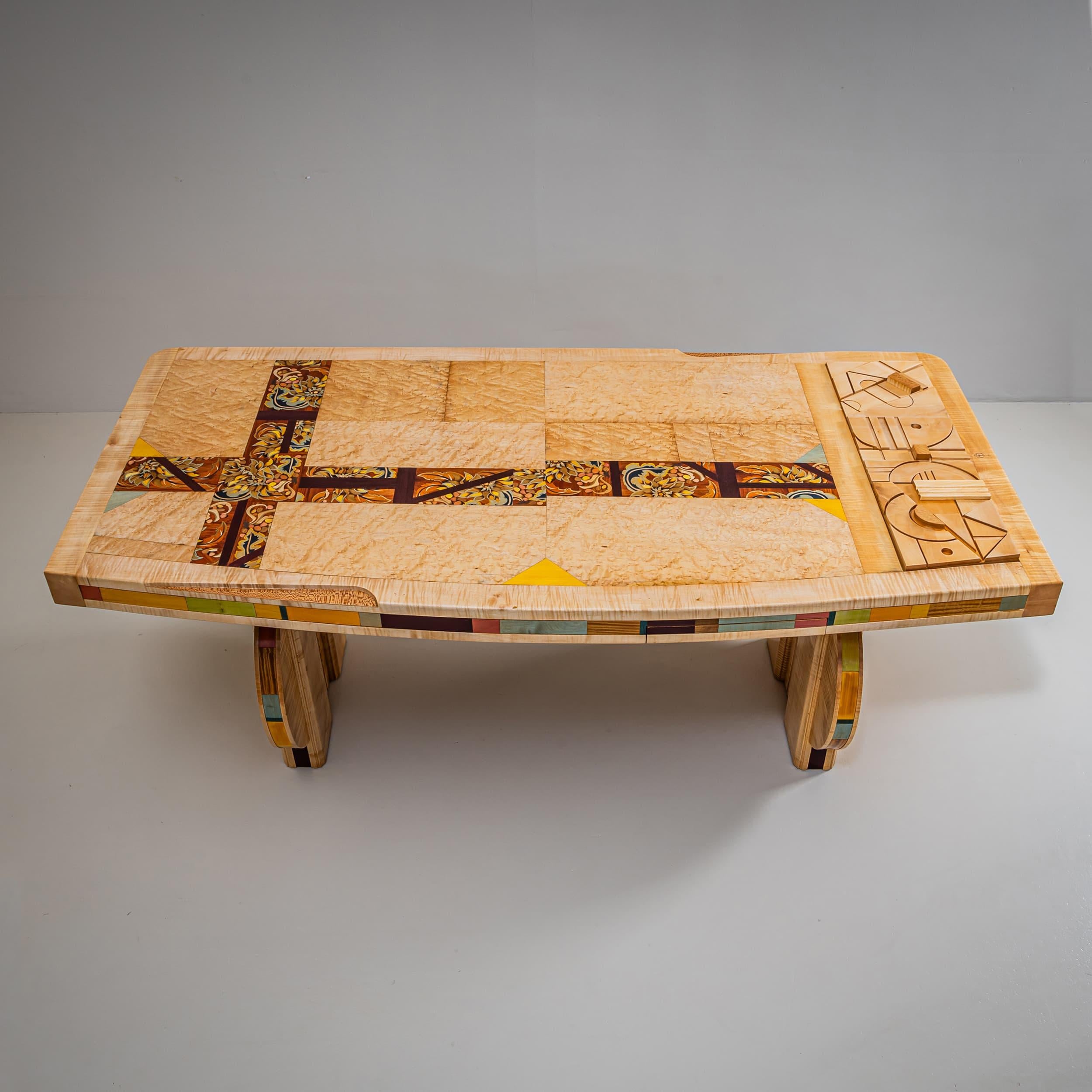 Ein außergewöhnlicher Schreibtisch von Alain François, der in den 1990er Jahren entstand. Entlang der Kanten sind bunte Intarsien aus verschiedenen gebeizten Hölzern angebracht, und auf der sanft gerundeten Oberseite befindet sich eine kreuzförmige