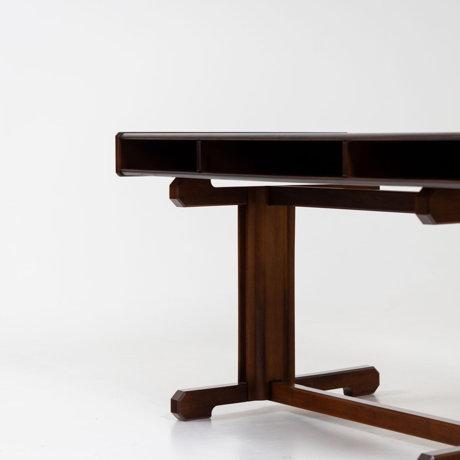Dark brown desk with two drawers designed by Gianfranco Frattini in the 1950s. The desk stands on a solid base frame with H-shaped bracing. The rectangular table top has two drawers with round knobs on the front and a central storage compartment.