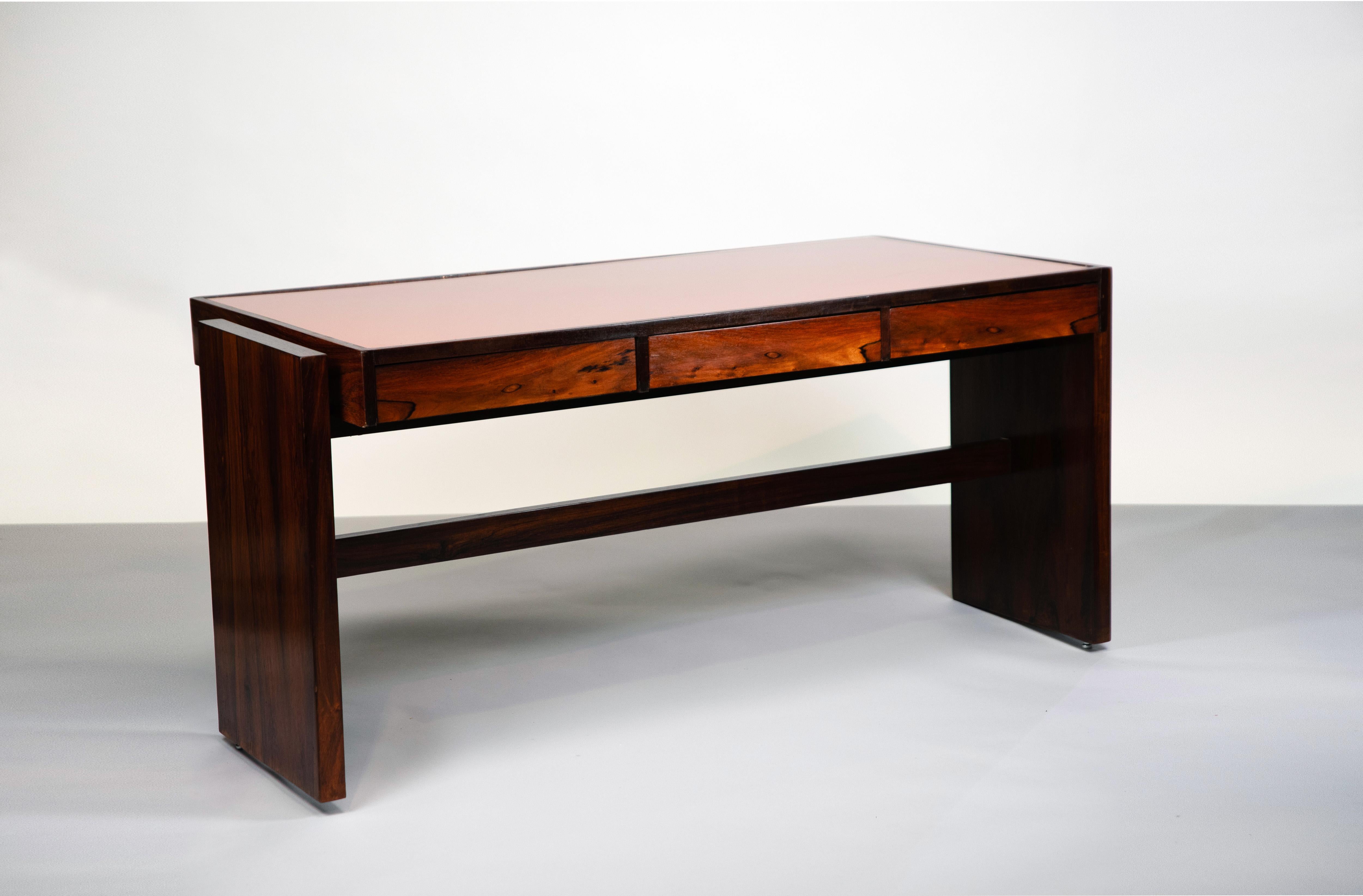 Desk in solid wood and wood veneer with three drawers resting on two straight legs in solid wood and attempted glass top in orange color. Desktop created specifically for Bloch Editors. Brazil, circa 1966 created in 1956 for a special order for the