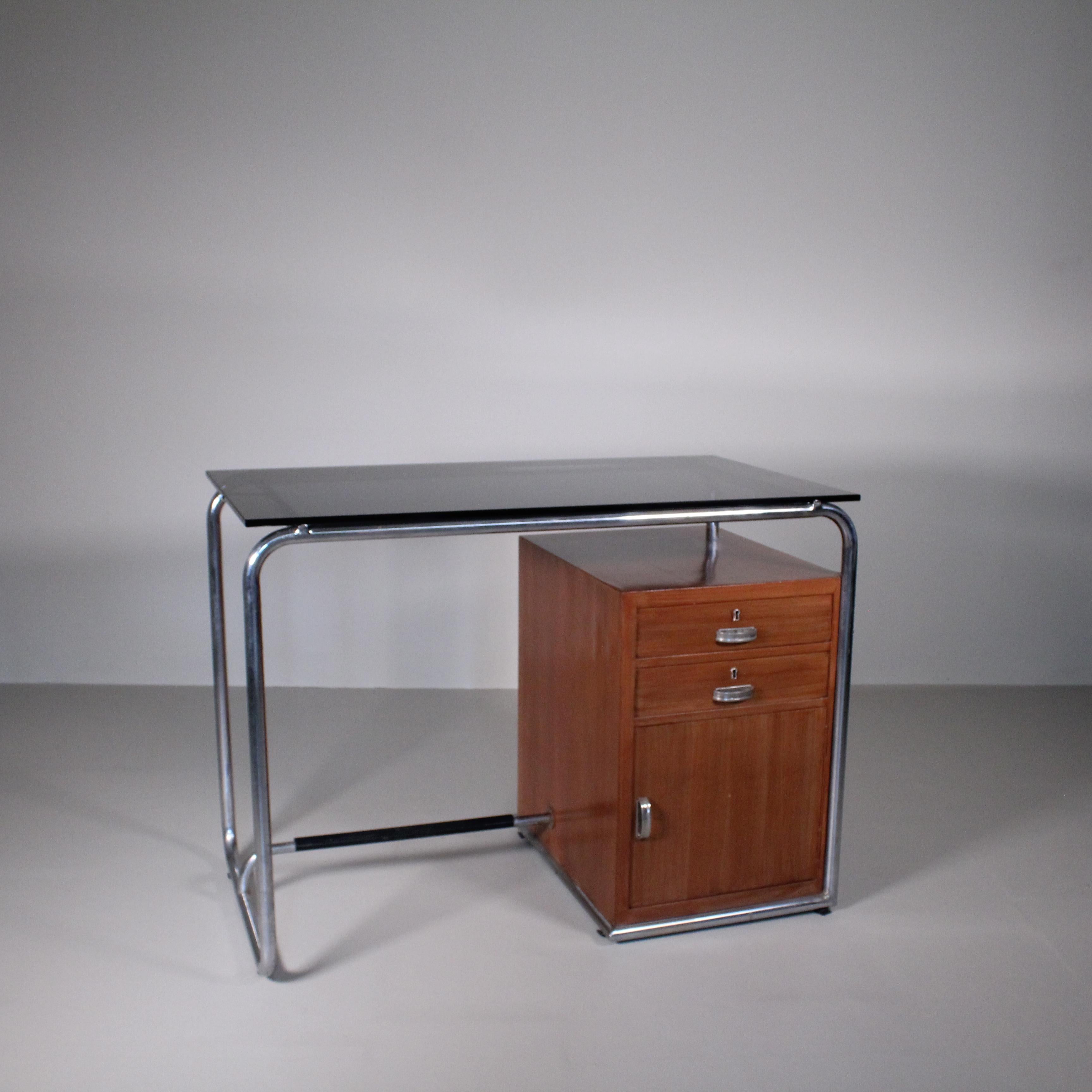 The 1960s functionalist style desk represents a fascinating piece of furniture that embodies the elegant marriage of functionality and aesthetics. This design object, with its tubular metal base, dark glass top, and wooden drawer unit, evokes the