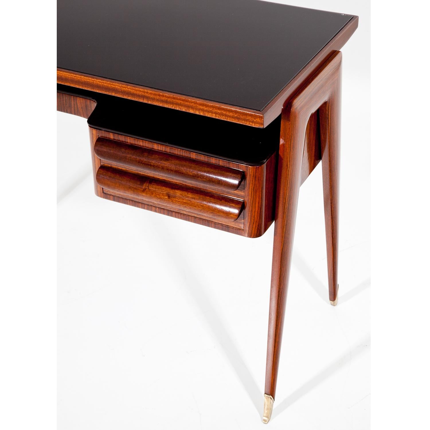 1950s Italian desk by Vittorio Dassi on elegant legs with brass sabots, two drawers to the right and a writing surface with glass top.