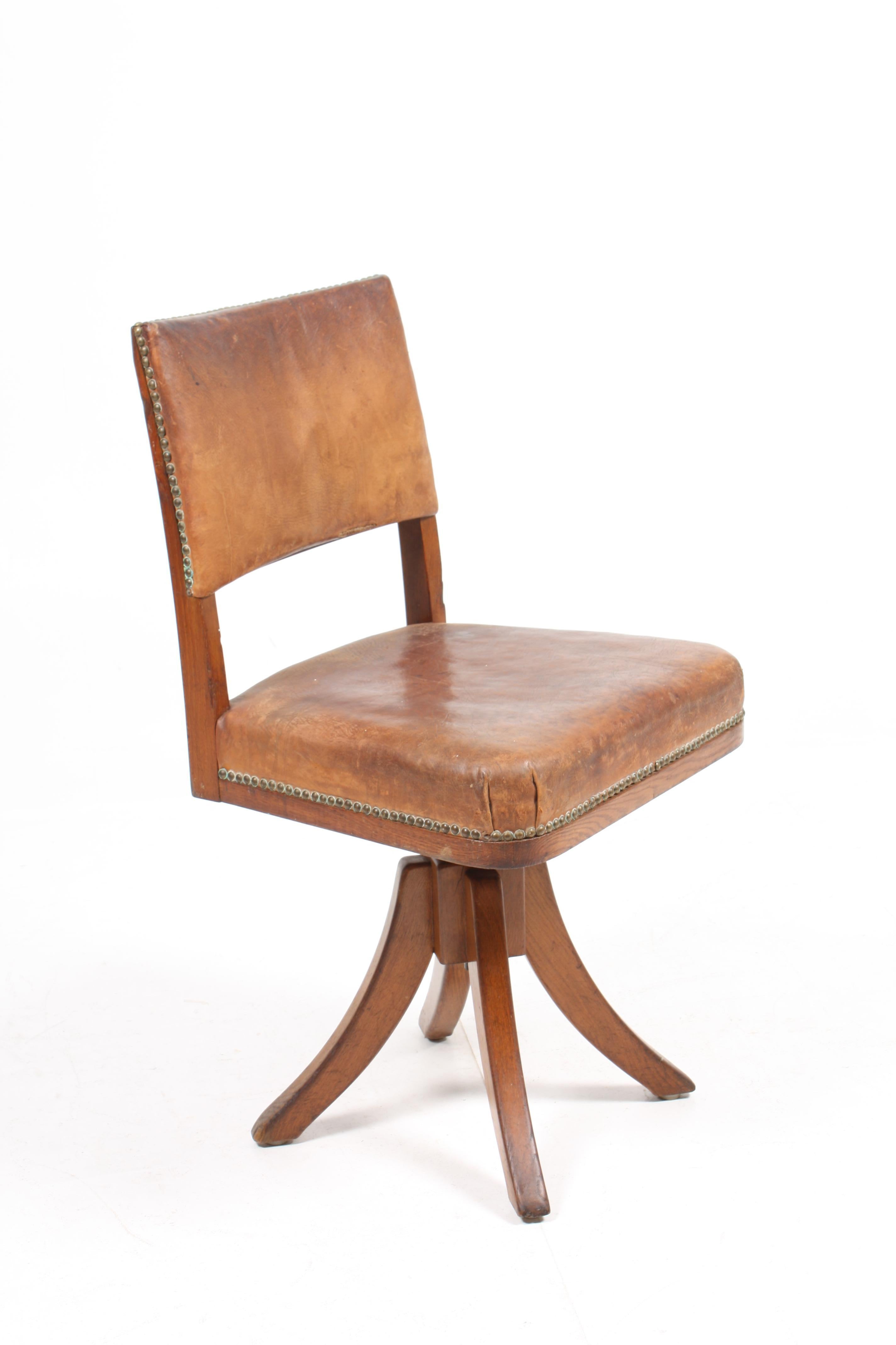 Swivel chair with adjustable height in patinated leather and oak. Designed and made by Frits Henningsen. Made in Denmark, great original condition.