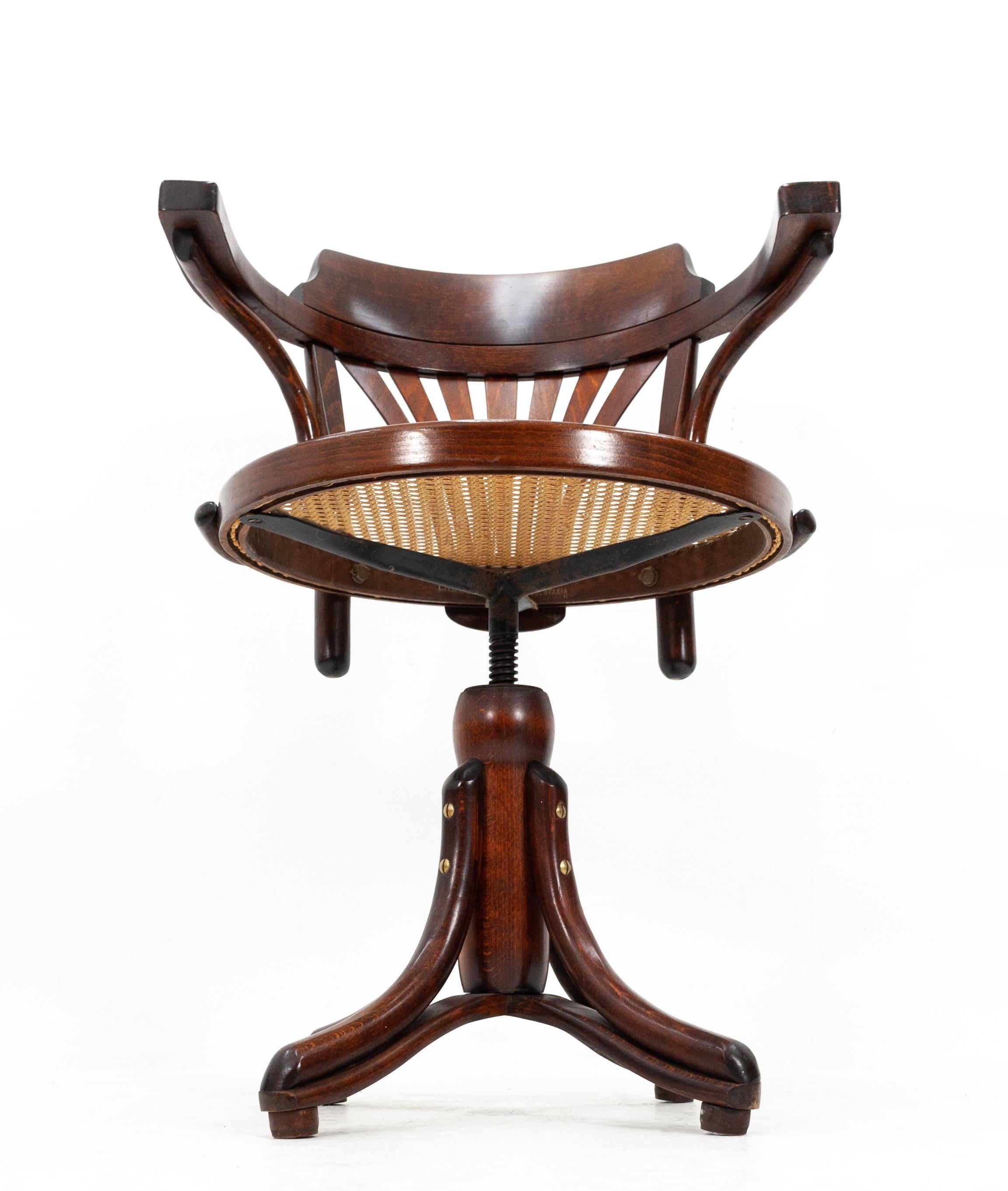 Revolving desk chair by Ligna in license for Thonet. Made in Czechoslovakia. 1950s. Solid beechwood.
Comes with a rattan seating. Remarkable good condition. Brass screws. Adjustable in height. and revolving.

 Measures: Seating height 47cm /