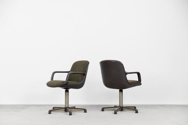 This pair of office armchairs was designed by Charles Pollock for the German manufacturer Comforto during the 70s. The seats are made of durable brown plastic and high-quality olive-colored fabric. A swivel leg or high armrests are the attributes of
