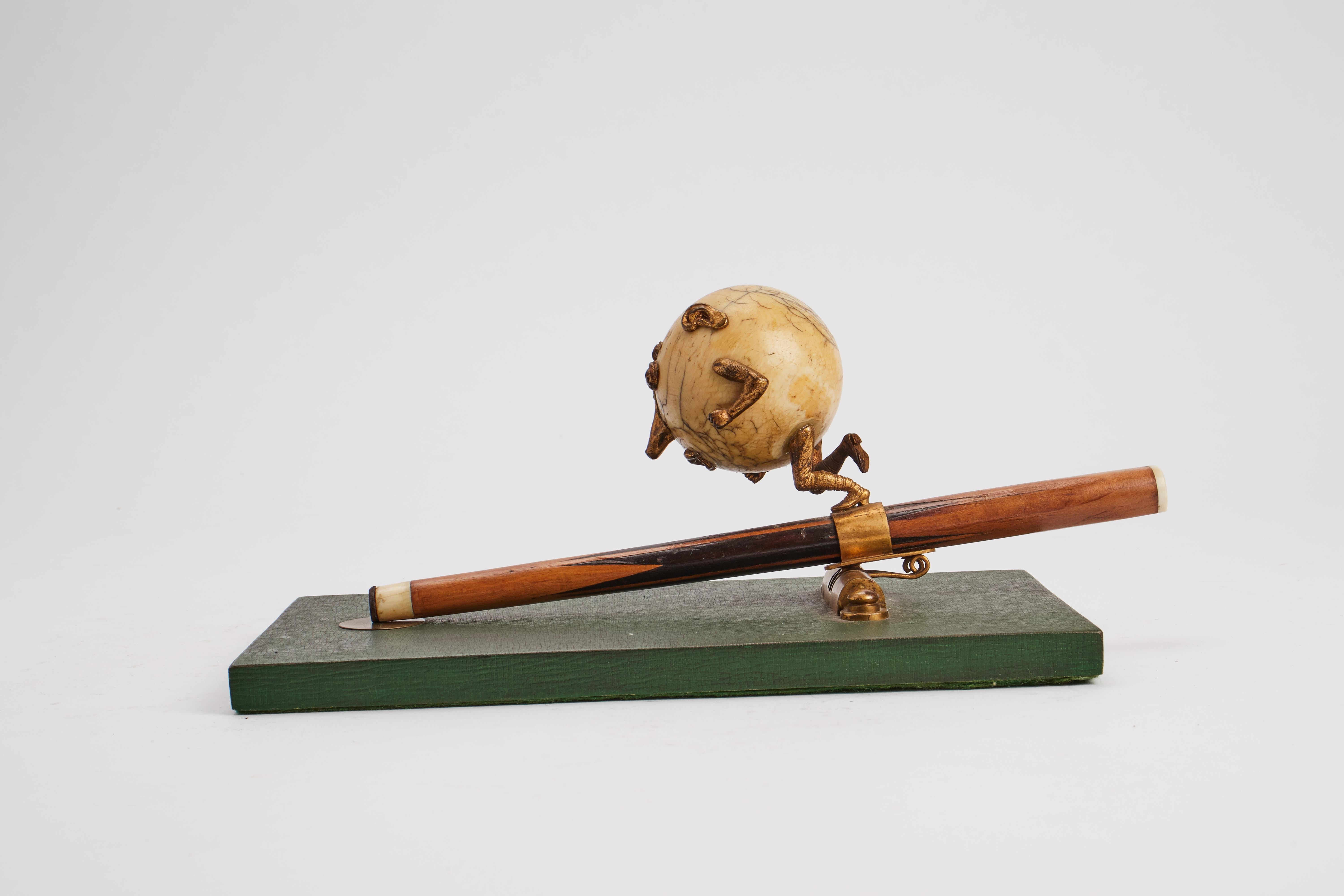 Wooden base, covered with green paper. A brass singe, with spring, holds the point of a billiard cue, over which runs the ivory billiard ball, as a caricatured face. England, end of 19th century. (SHIP TO EU ONLY)