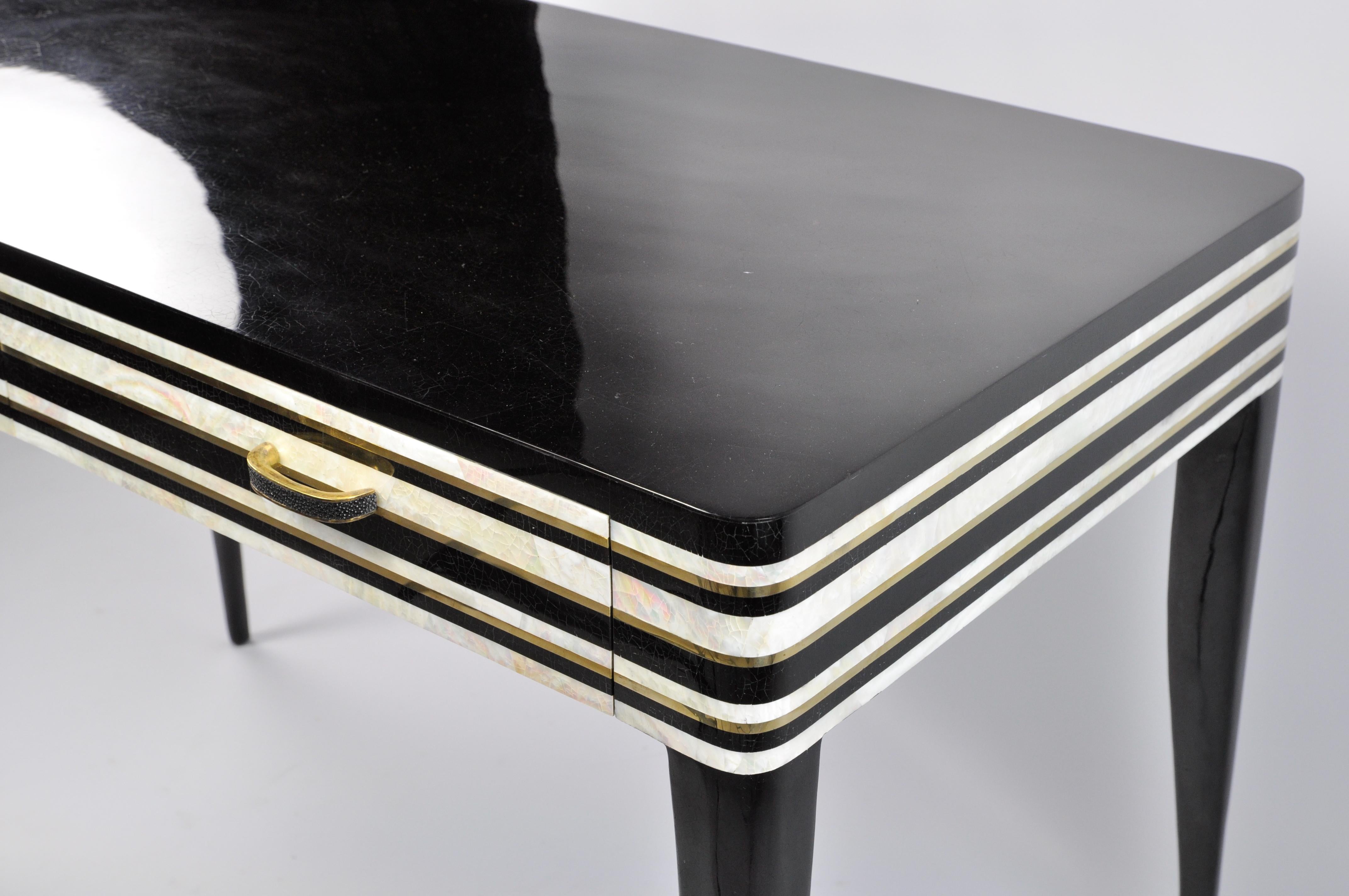 This desk is made of black and white polished shell marquetry with brass trims.
It has 2 drawers with brass and shagreen handles.
The legs are in black polished shell marquetry.
It can be used as a writing desk or as a vanity table in a