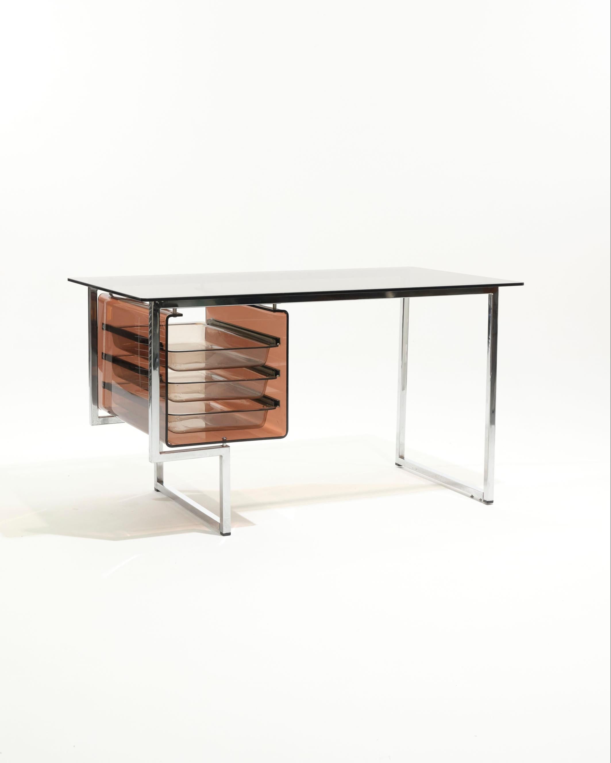 Desk with smoked glass top resting on a chrome metal frame, 1970s.
Features a three-drawer compartment in smoked plexiglass.
An iconic 1970s/80s aesthetic, combining transparency with structured lines.
In good overall condition, with some scratches