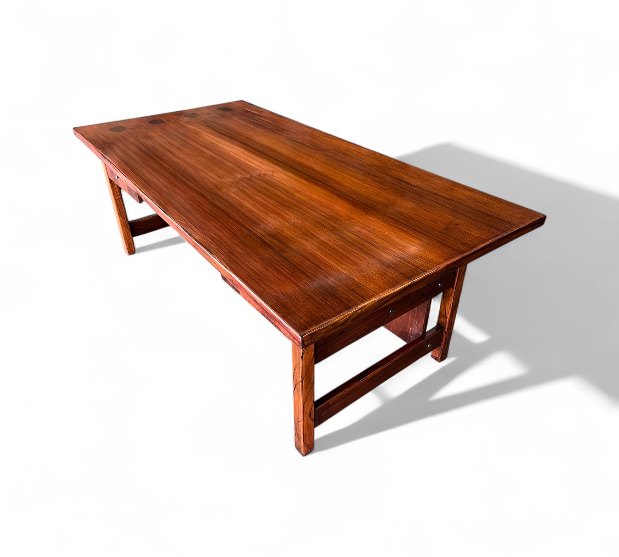This elegant desk is crafted from solid hardwood and was designed in Brazil during the 1960s. It features a rectangular top, two spacious drawers, and four sturdy rectangular legs. The wood has been refinished, and the piece is in excellent