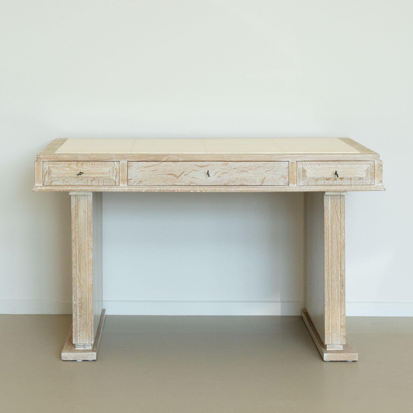 Chalked oak desk with inset beige top and three drawers.
