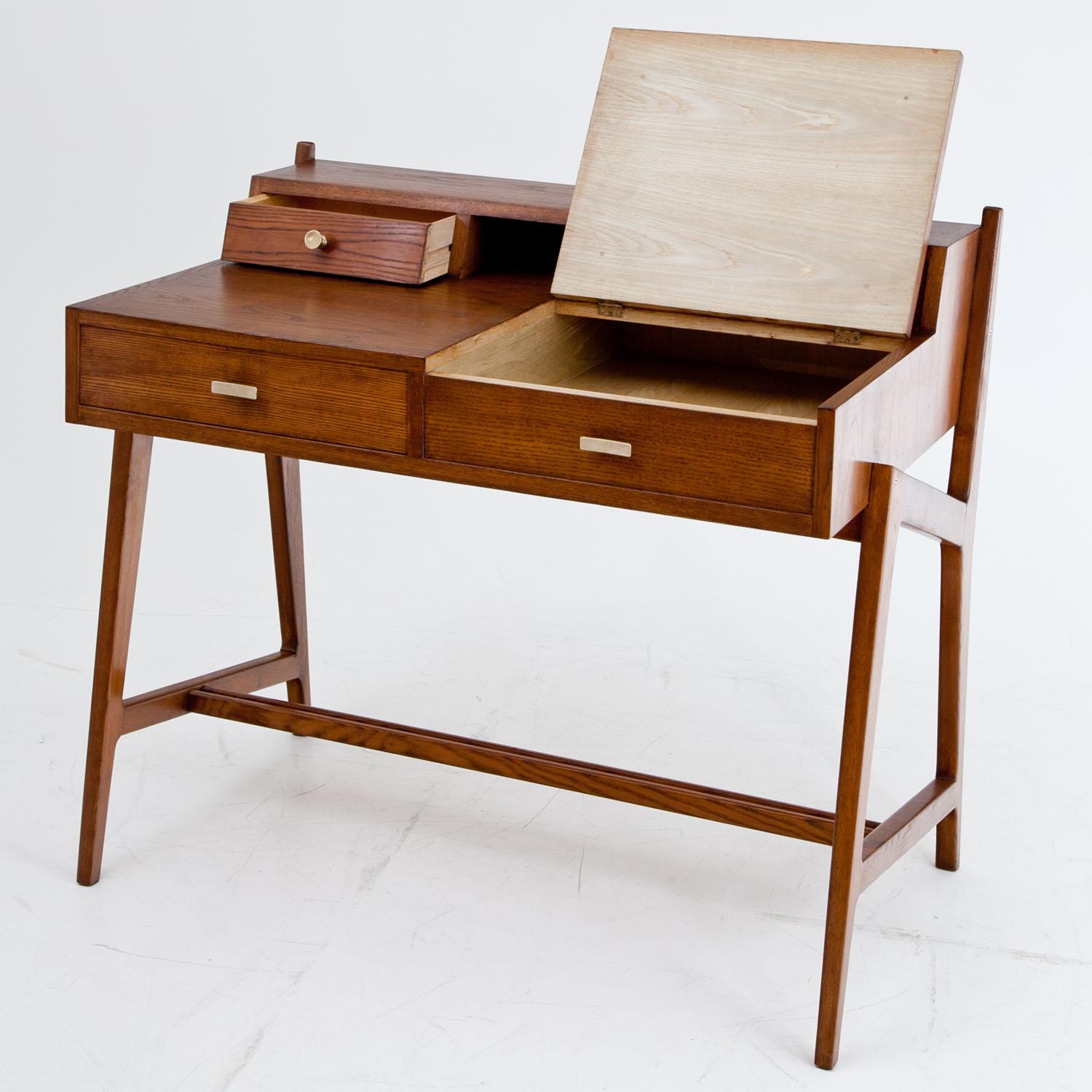 Small desk with three drawers and one compartment with hinged lid in a used condition.