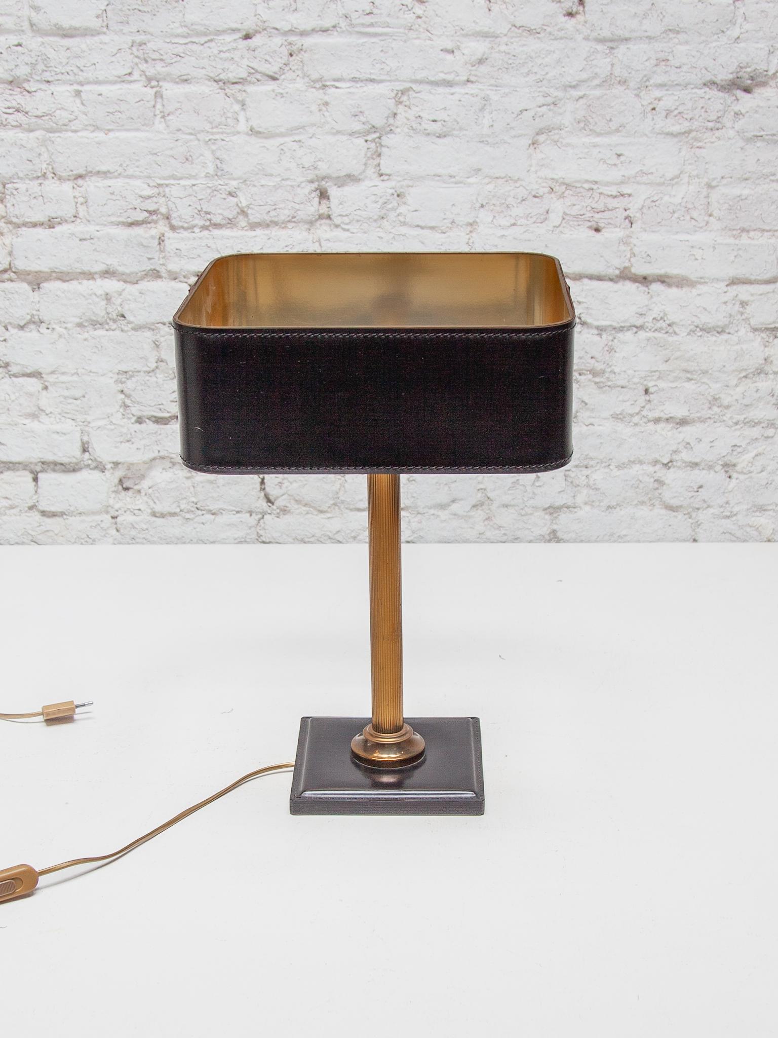 This very nice desk lamp is made of black leather and brass. A very elegant model lamp for your desk or sideboard in your living room or office in the style of the French designer Jacques Adnet. Circa 1970.

