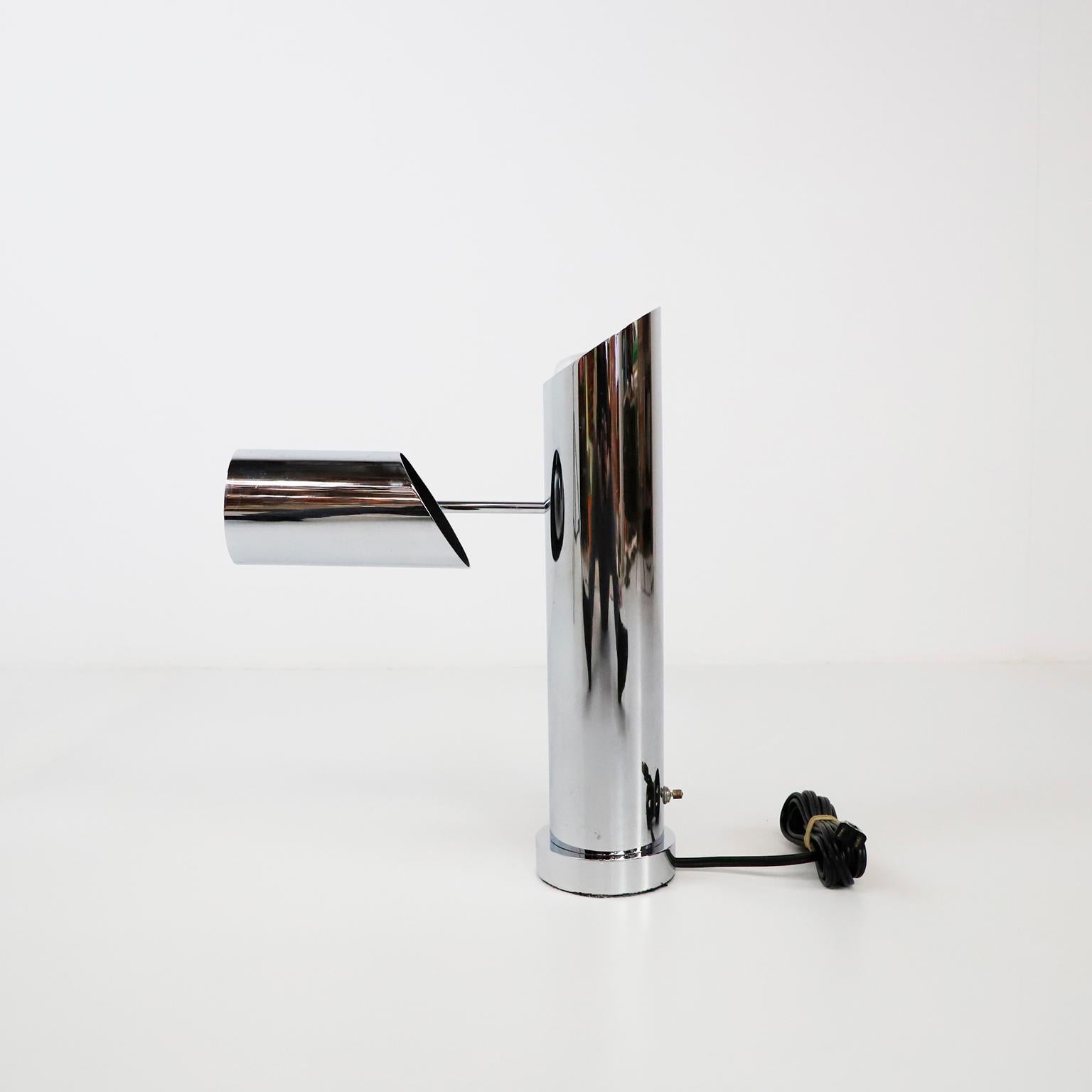 An interesting chrome-plated table lamp, designed by Angelo Lelli for Lightolier, circa 1960s. The cylindrical body of the lamp is bisected diagonally, with a light source in the bottom section directed upwards and a light source in the top section
