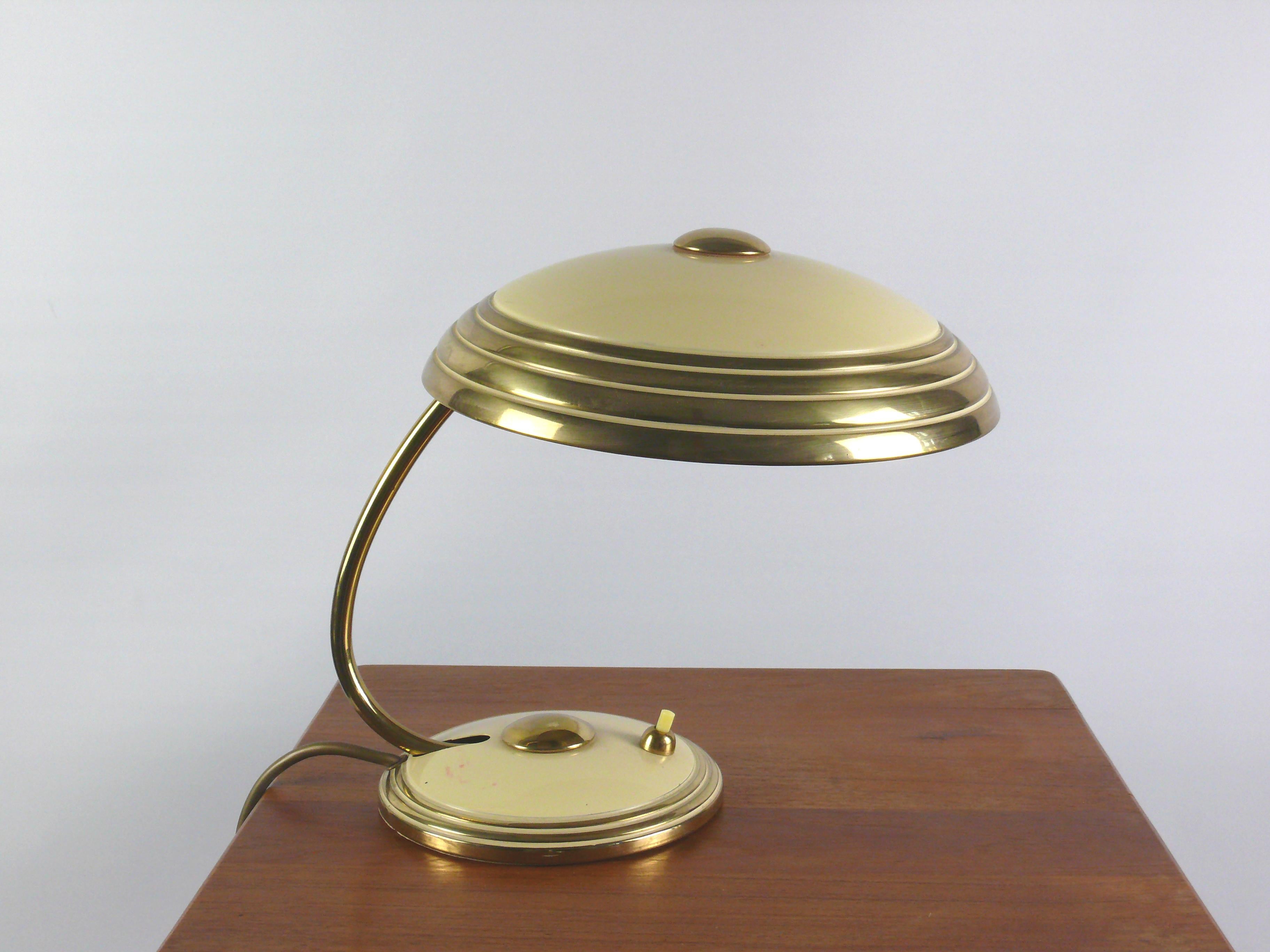 Well-preserved Helo table lamp, a timeless classic from the 1950s. The slight difference between the beige, painted areas and the shiny brass parts gives the lamp a noble calm. Stylistically, the design of the lamp is based on the Bauhaus period.