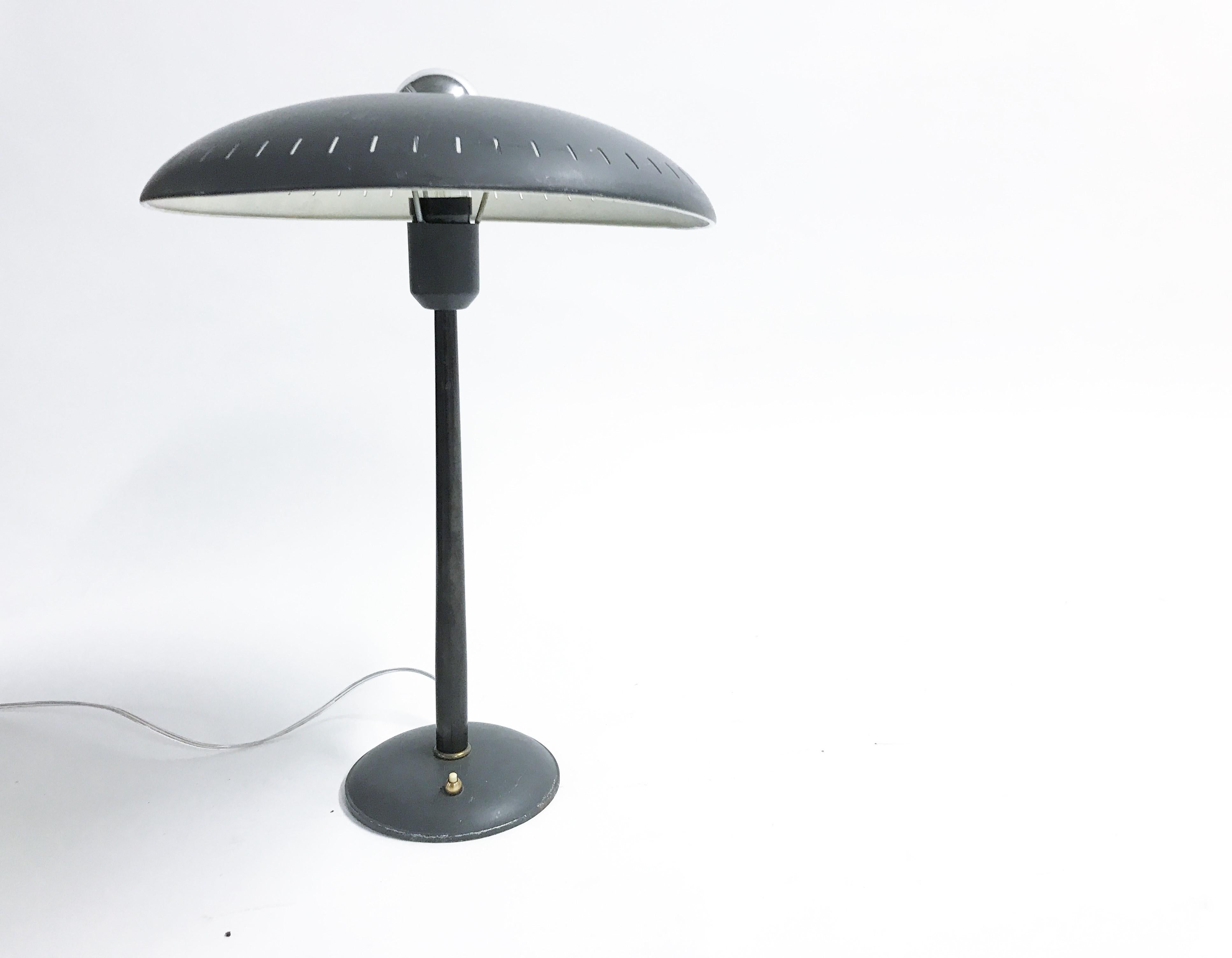 Midcentury table lamp designed by Louis Kalff for Philips.

The lamp consists of a round cast iron base with a black steel rod and a enamelled perforated aluminum lamp shade.

The lamp shade has a 'ufo' design, typical for the space age era and