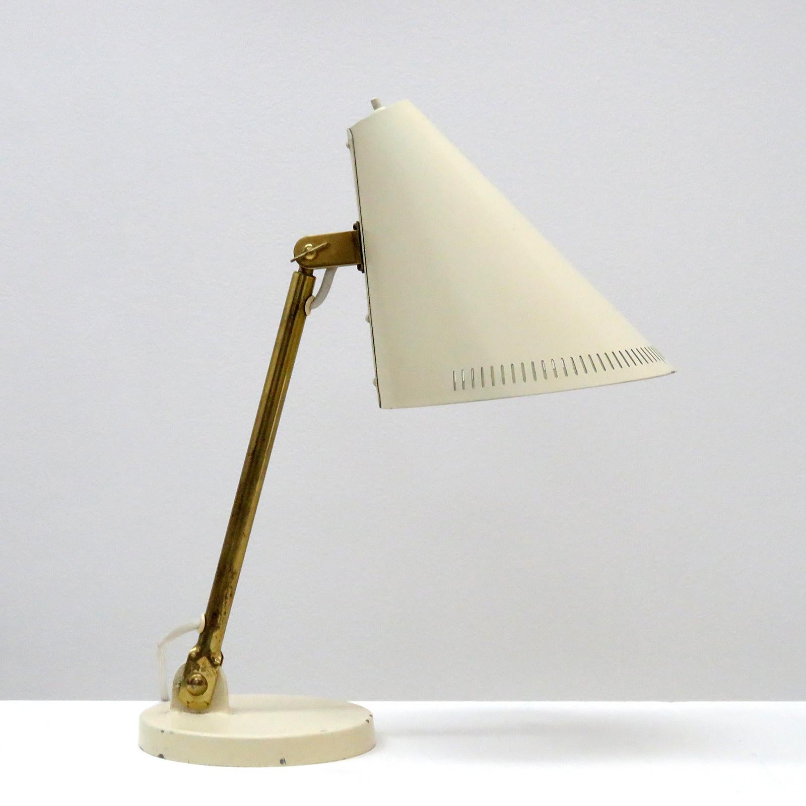 Wonderful early desk lamp model 5305 by Paavo Tynell for Taito, Finland, with a large articulate crème colored enameled shade and base, the shade is partially perforated and the brass arm is adjustable, stamped OY Taito 9222 at the shade.