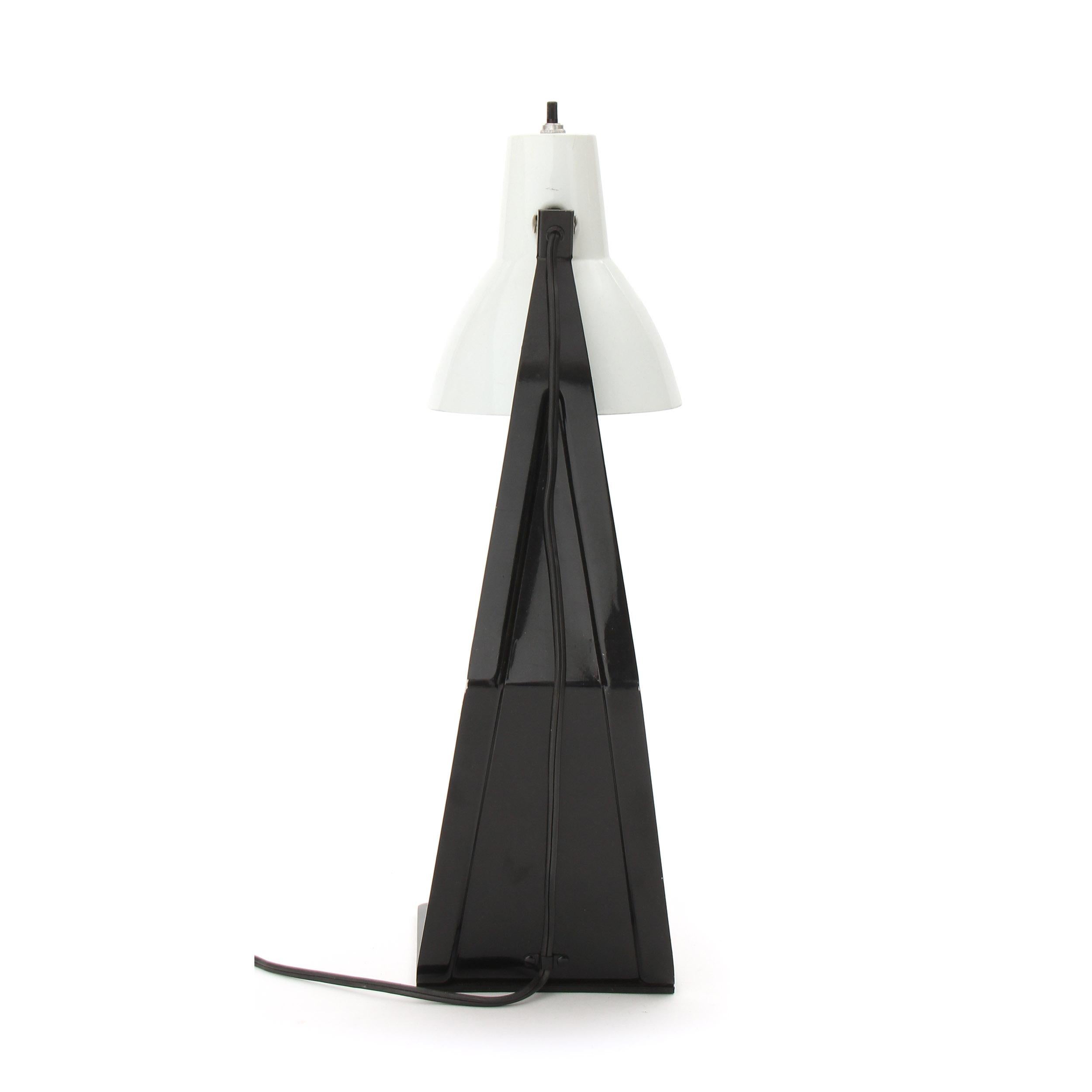 A desk / table lamp made of a singular stamped, die cut and folded piece of metal, painted black with a pivoting shade.