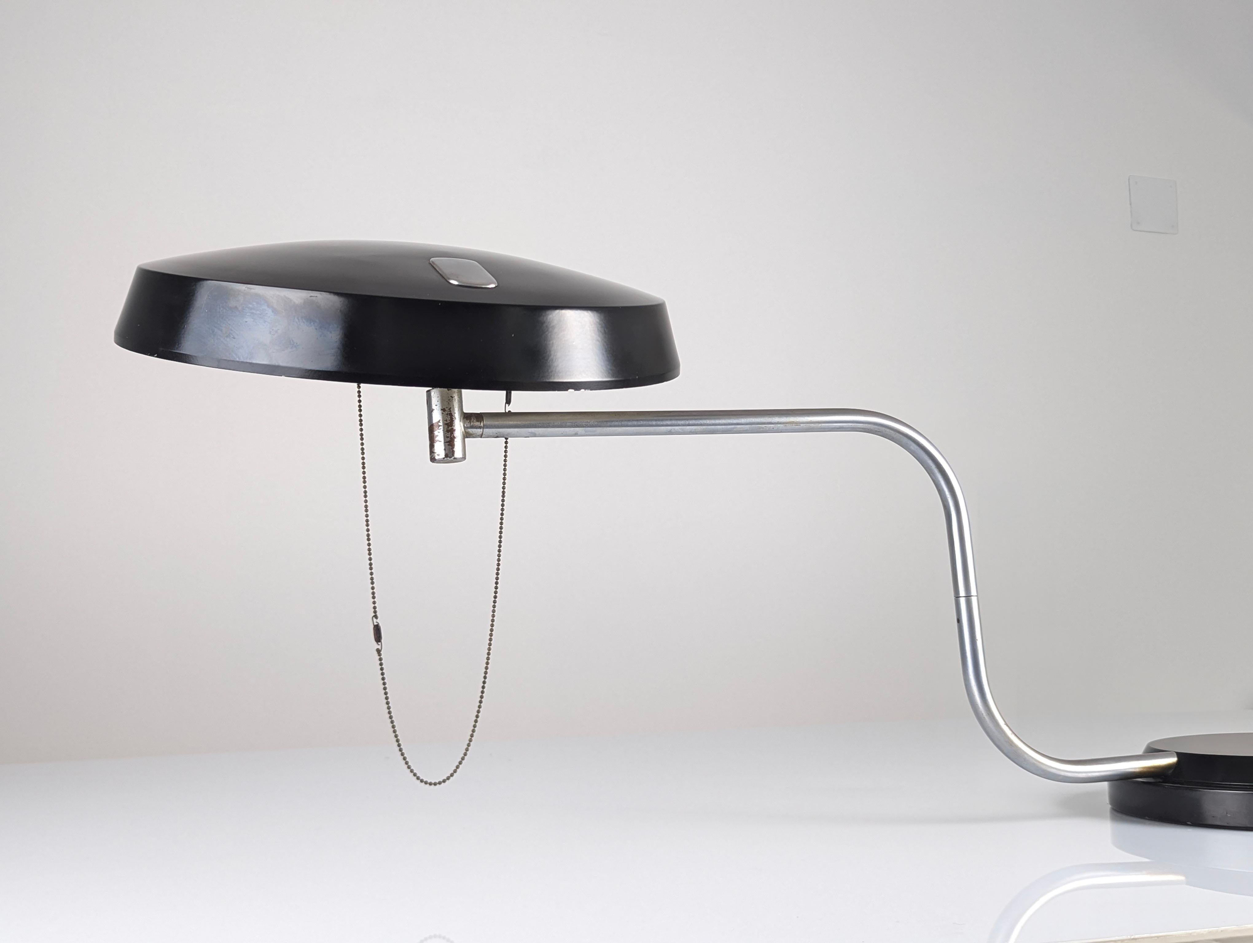 Questa lampada da scrivania, disegnata da Enrique Aparicio per Galaxia nel 1961, ha ricevuto il prestigioso Delta Gold  Design/One nel 1962. Presenta un design raffinato che offre grande flessibilità e illuminazione grazie ai tre punti di rotazione
