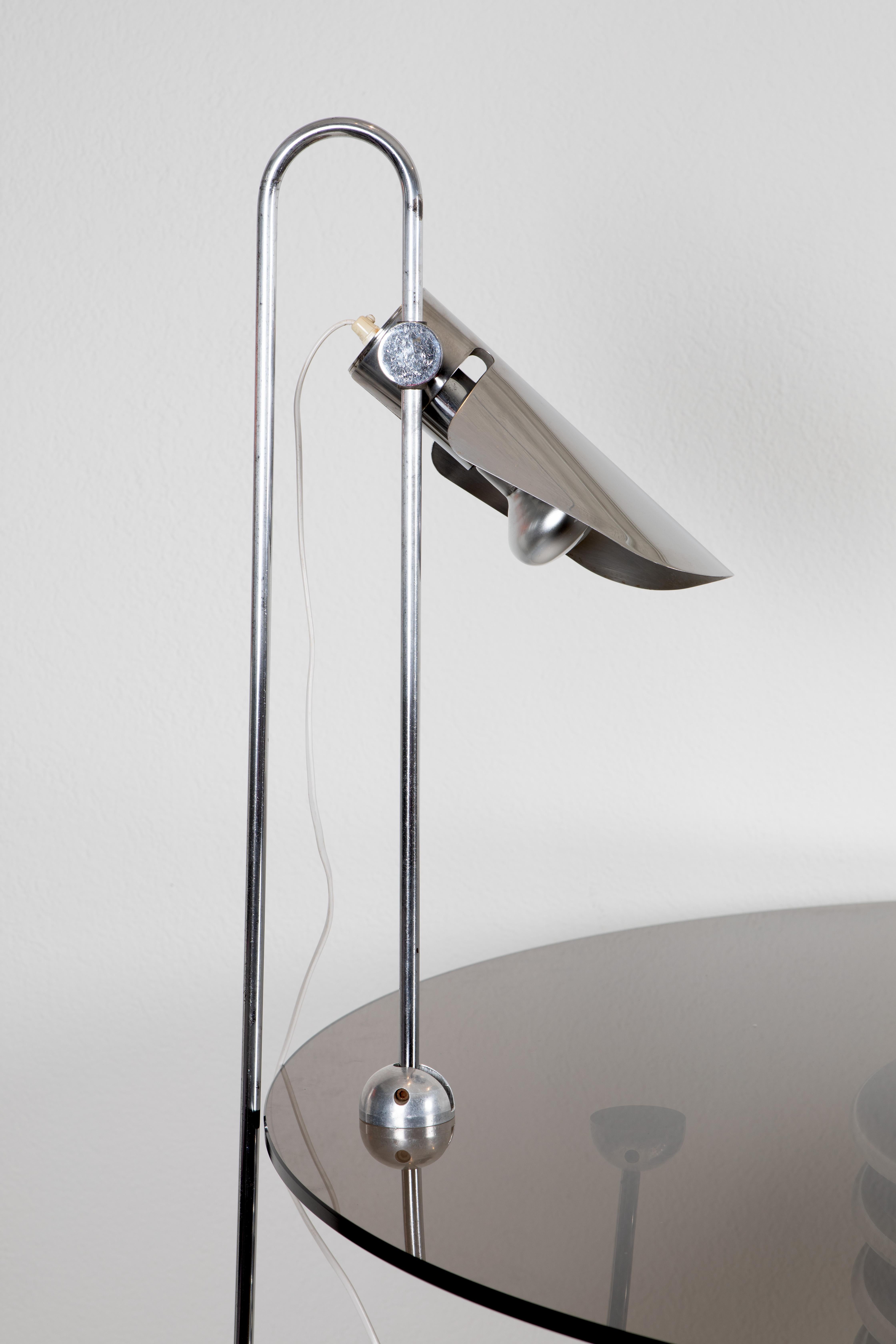 This unique desk lamp from the 1970s features a counterbalanced structure and a clever design that uses a paperclip to support a reflector, giving it an industrial yet minimalist appeal. The chromed metal finish enhances its sleek, modern look,