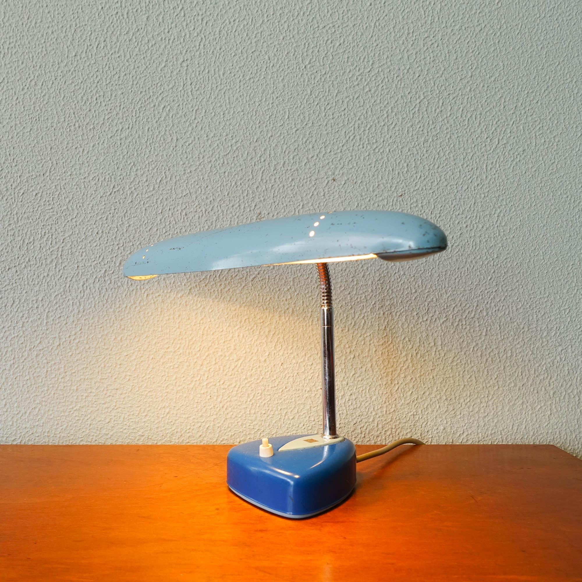 This desk lamp was designed and manufactured by National Matsushita, in Japan, during the 1960s. The lamp has a light blue shade, dark with light blue foot and chrome, movable gooseneck. It is marked on the foot. In original and good vintage