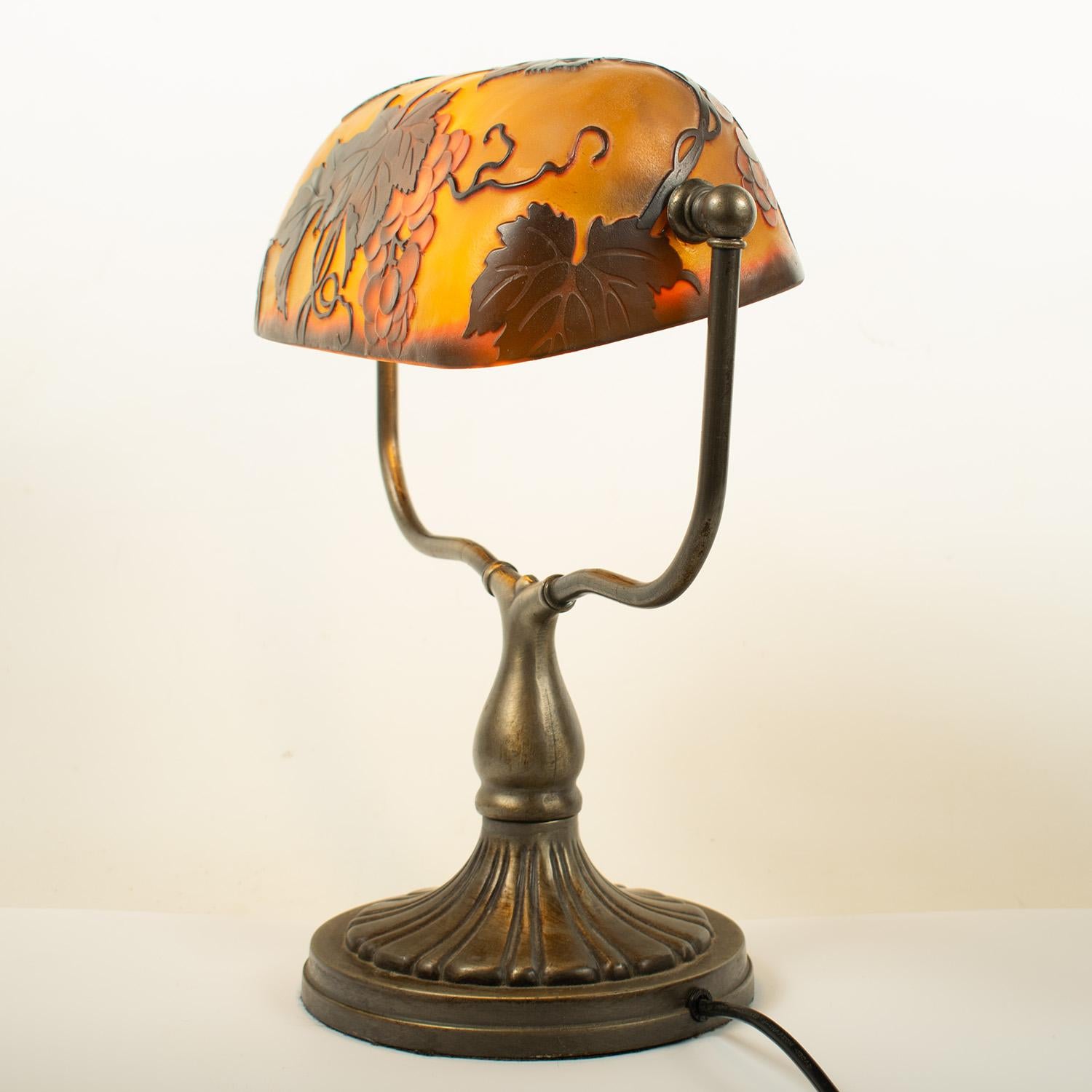Art Nouveau Desk lamp in the style of Emile GALLE, multilayer glass lampshade with acid-etched decoration of vine branches in muted yellow, orange and green tones.

This is a more recent lamp in the Art Nouveau style most probably produced in the